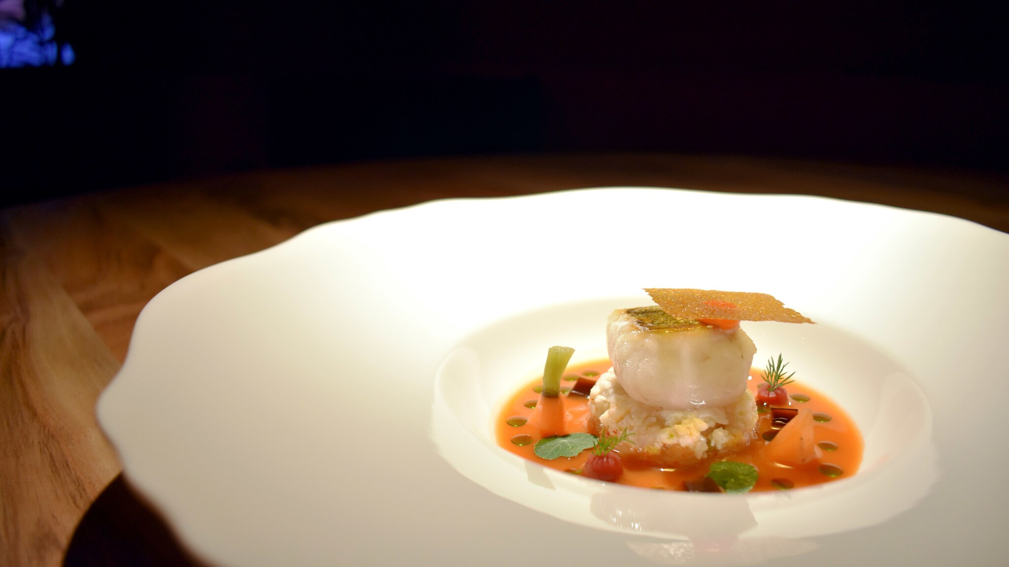 Ein Fischgericht, edel angerichtet auf einem großen weißen Teller.