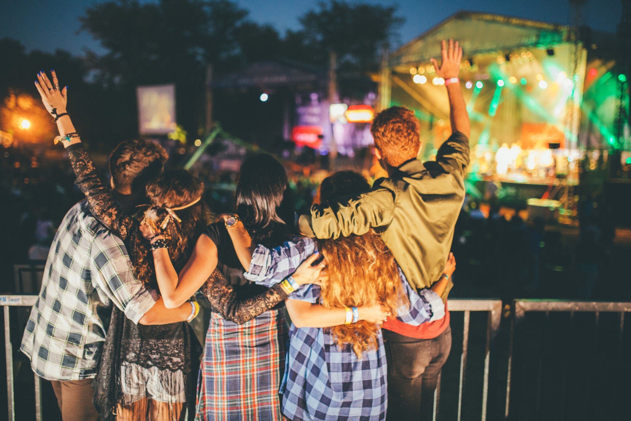 Jubelnde Zuschauer von hinten vor einer Bühne auf einem Musikfestival bei Nacht.