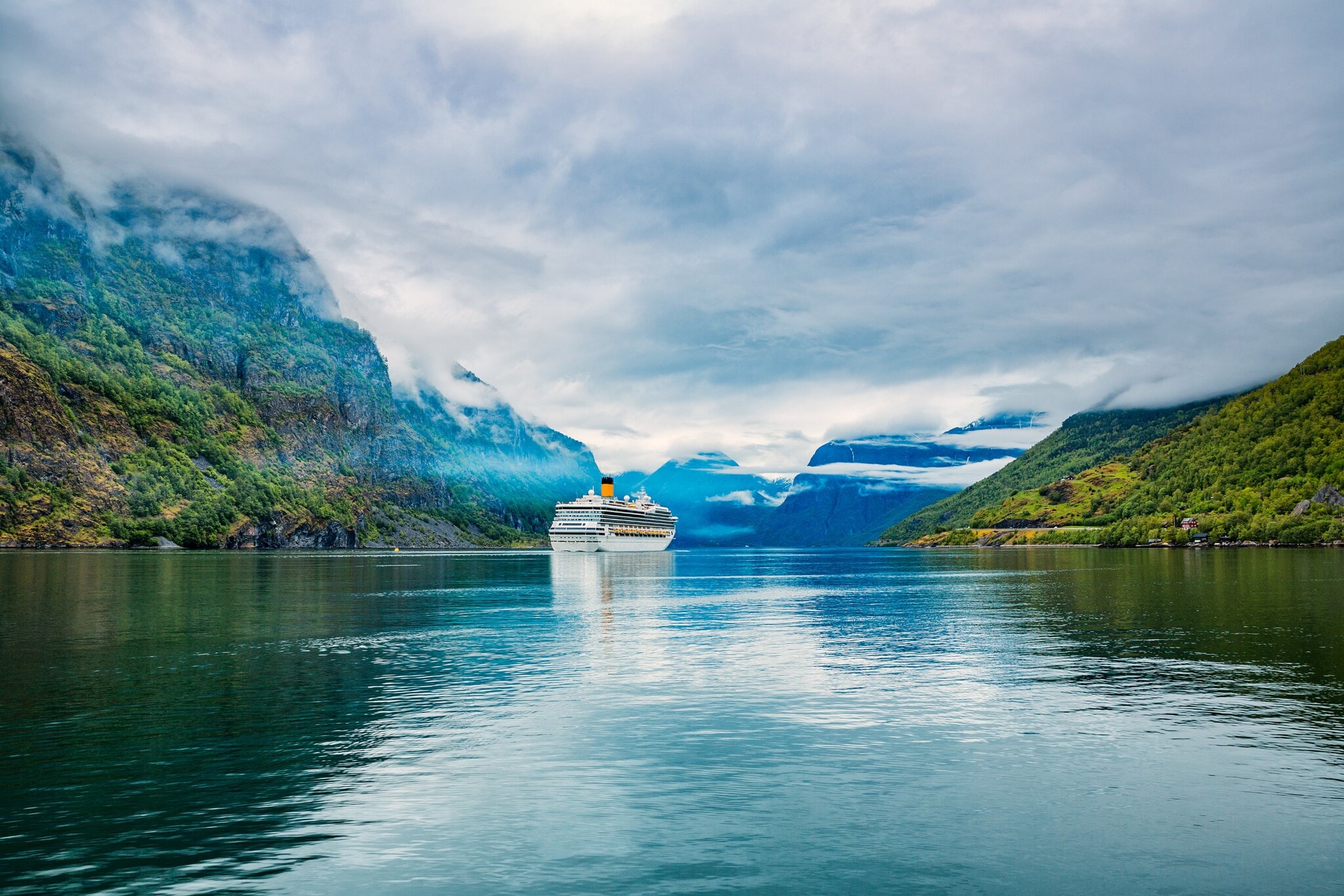 Ein Kreuzfahrtschiff in einer Fjordlandschaft unter bewölktem Himmel. Ein Kreuzfahrtschiff in einer Fjordlandschaft unter bewölktem Himmel.