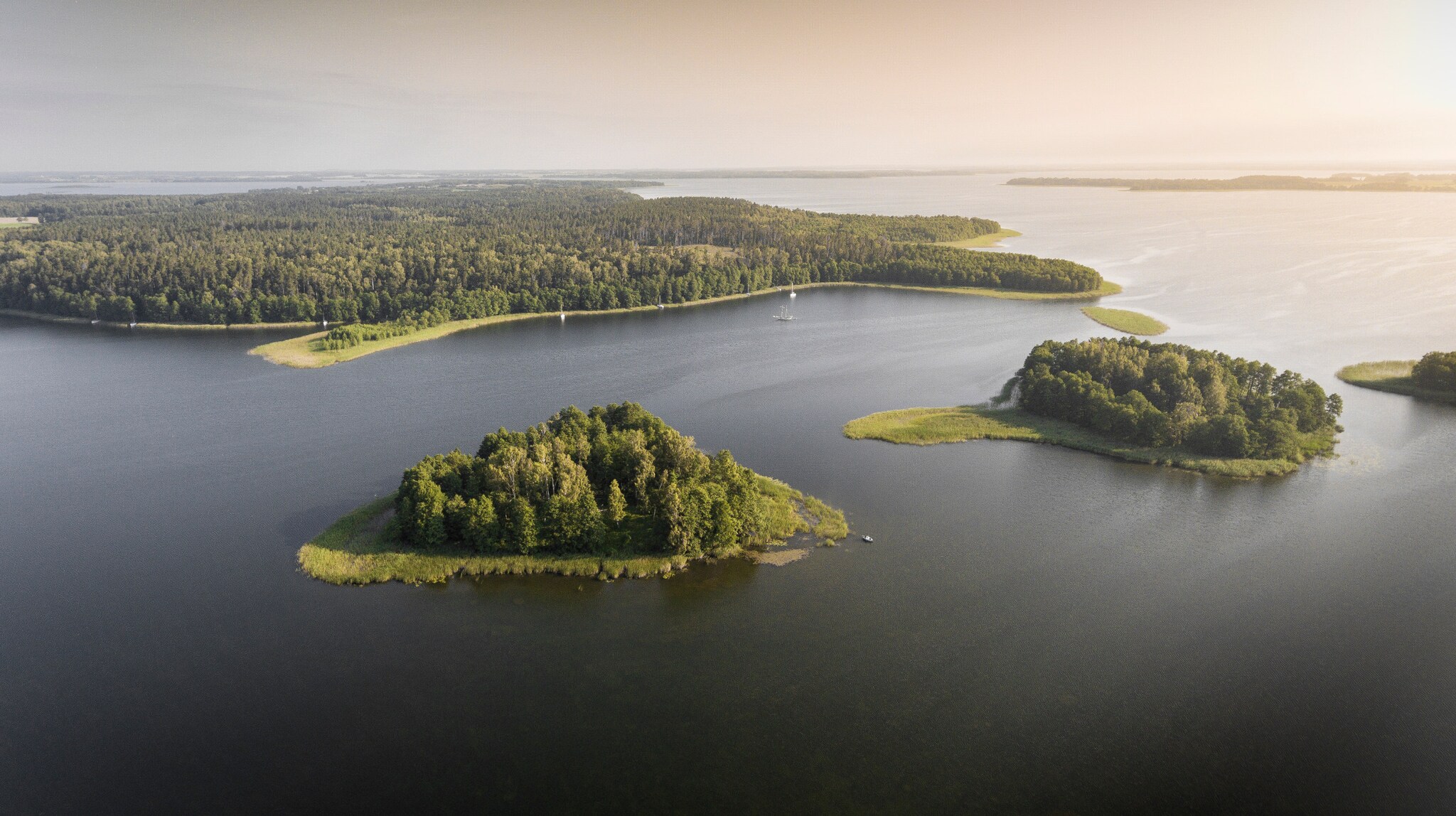 Luftaufnahme mit kleinen grünen Inseln im ruhigen Wasser der Masurischen Seenplatte. Luftaufnahme mit kleinen grünen Inseln im ruhigen Wasser der Masurischen Seenplatte.