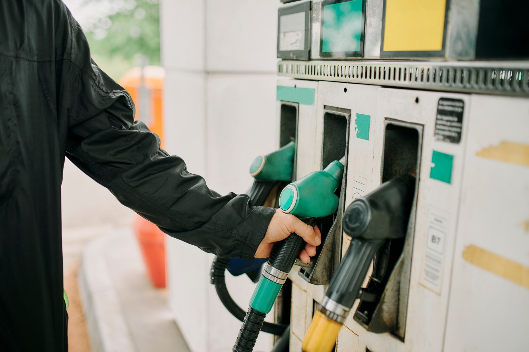 Close-up – Mann greift nach einem Zapfventil an einer Tankstelle. Close-up – Mann greift nach einem Zapfventil an einer Tankstelle.