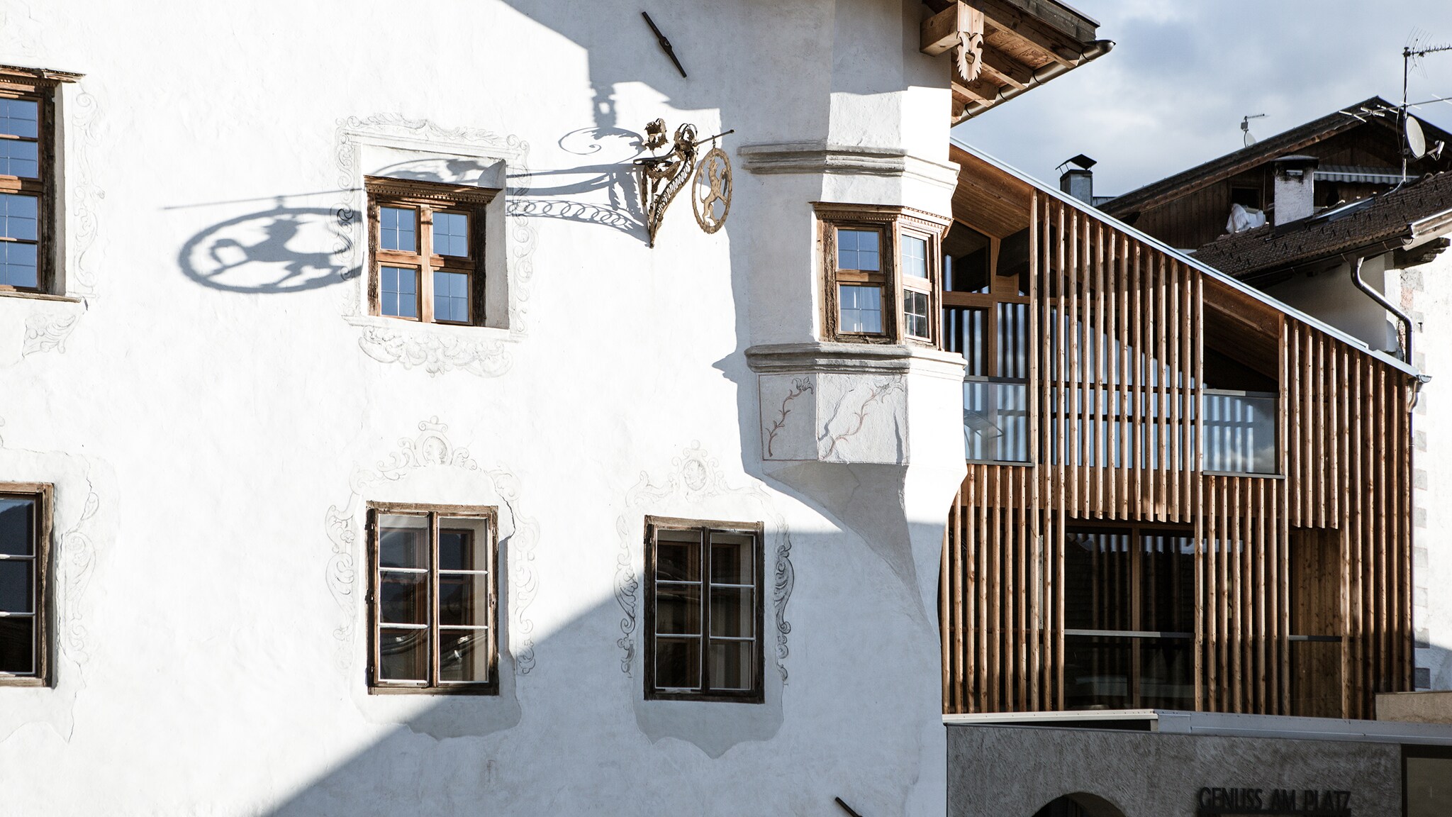 Gebäudekomplex mit weißer, historischer Fassade und moderner Architektur mit Holzdetails.