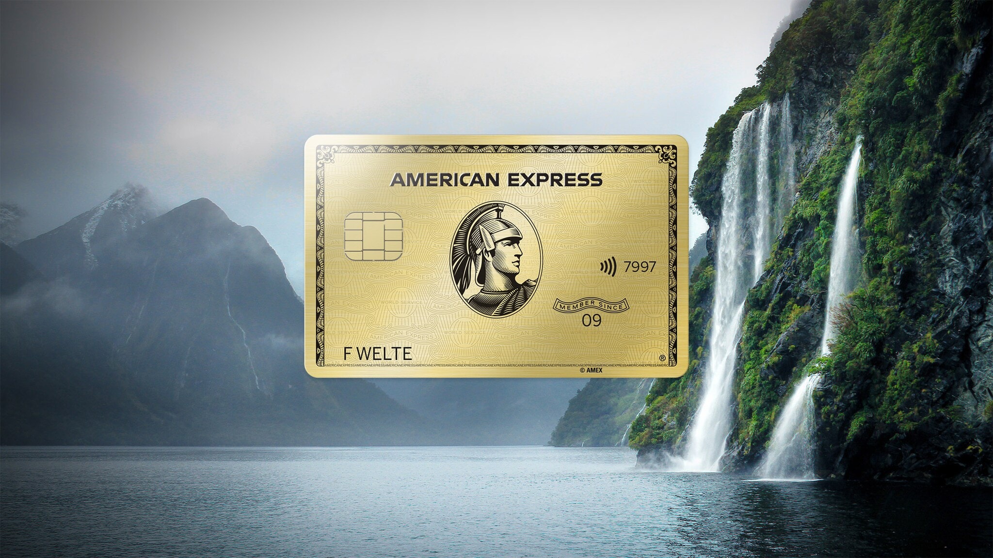 Fotocollage mit einer goldenen Kreditkarte von American Express vor einer nebeligen Berglandschaft an einem See mit Wasserfall. Fotocollage mit einer goldenen Kreditkarte von American Express vor einer nebeligen Berglandschaft an einem See mit Wasserfall.