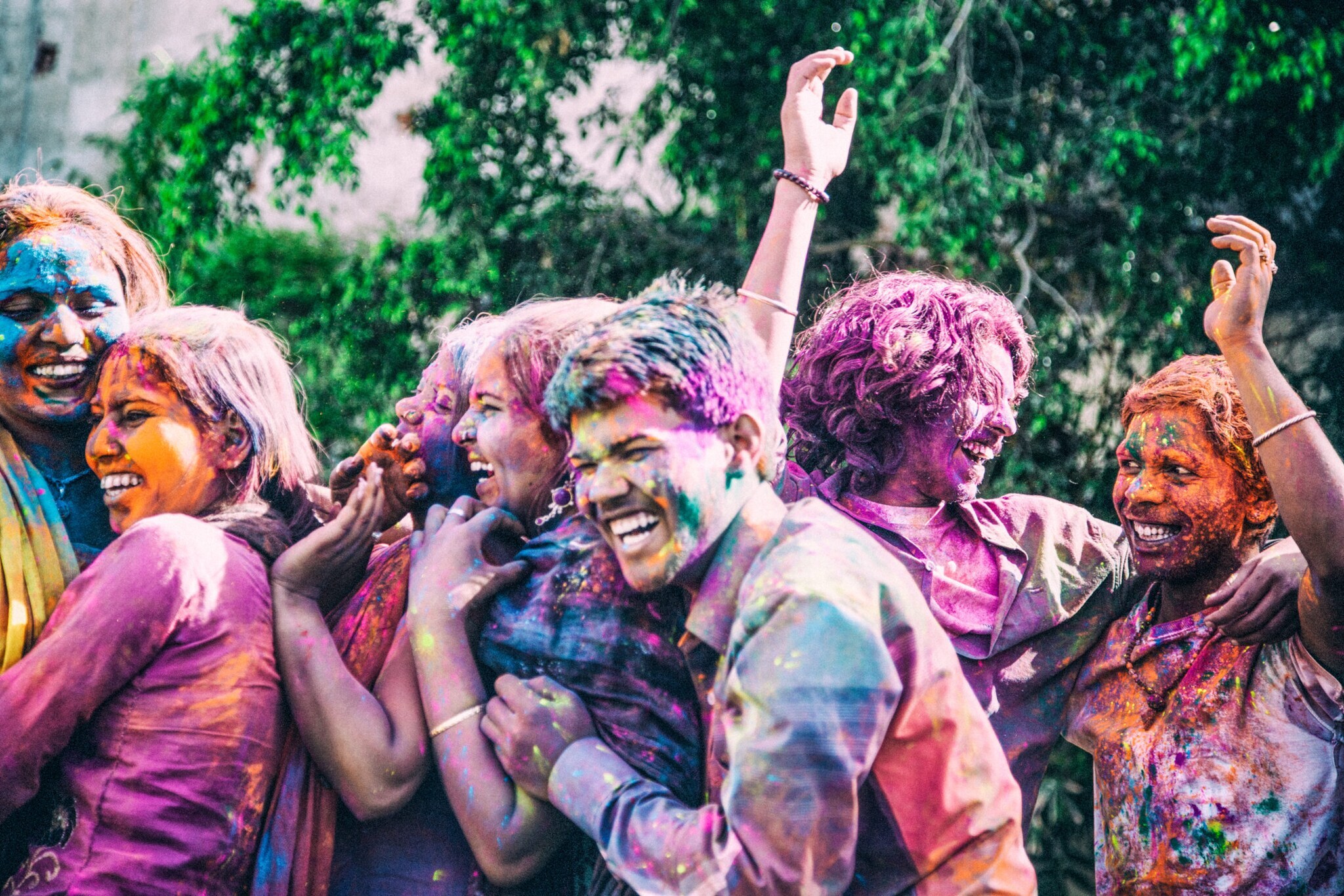 Lachende Personen indischer Abstammung voll mit bunter Farbe auf einem Holi Festival.