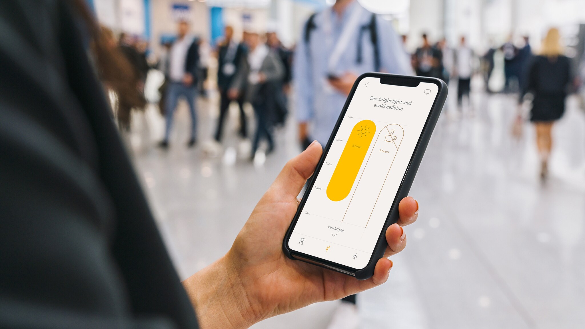 Nahaufnahme eines Smartphones mit Timeshifter App in der Hand einer Person in einem Flughafenterminal.