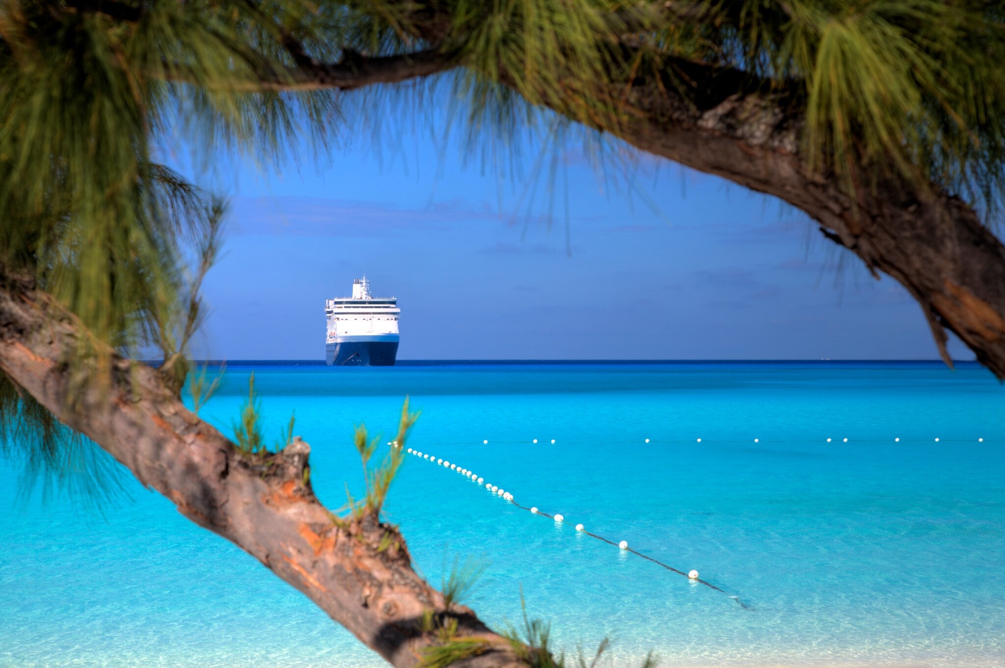 Kreuzfahrtschiff am Horizont eines Karibikstrands mit klarem türkisfarbenem Wasser. Kreuzfahrtschiff am Horizont eines Karibikstrands mit klarem türkisfarbenem Wasser.