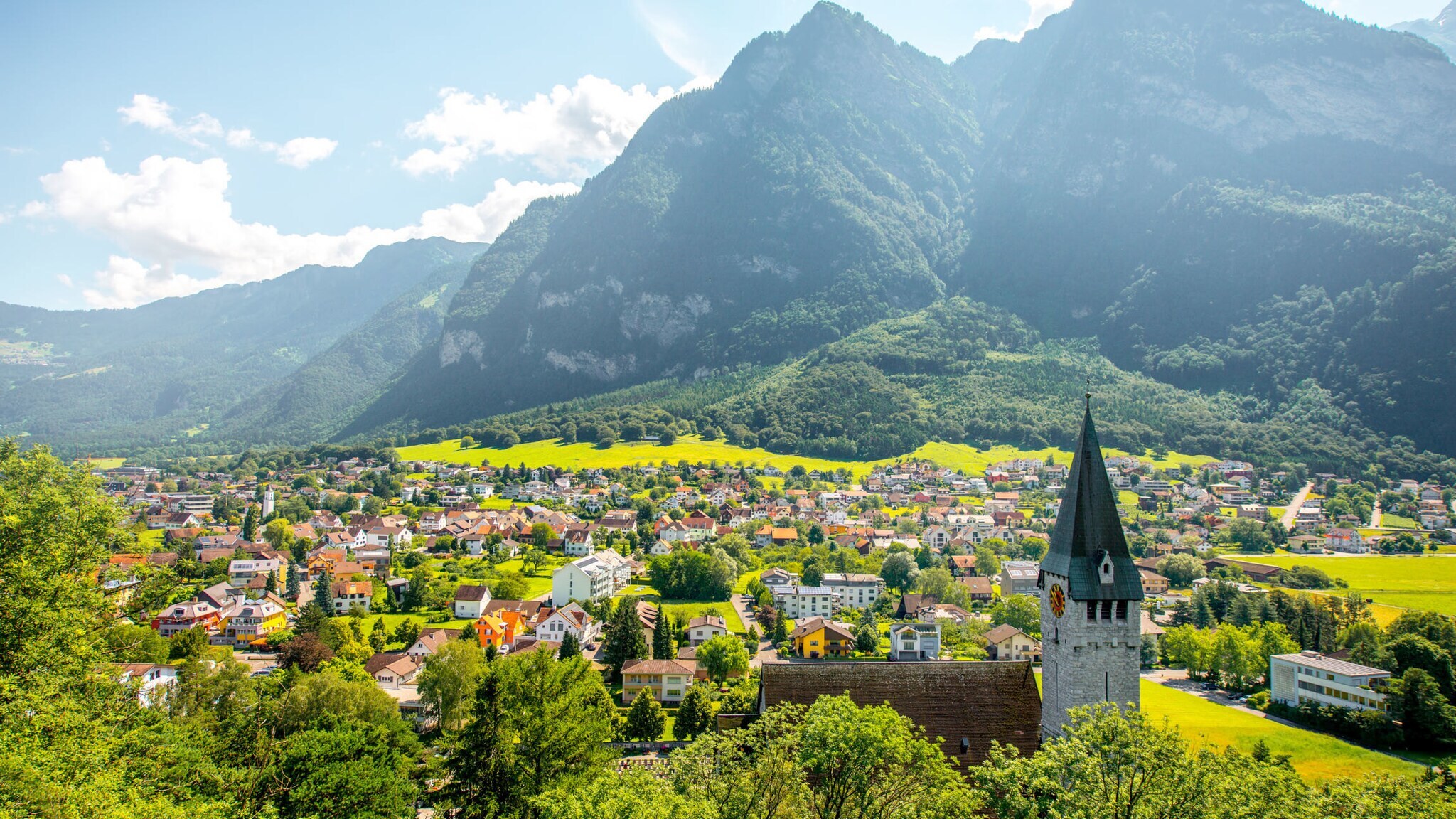 Landschaftsaufnahme eines Tals in Liechtenstein mit Kirche, vielen Häusern und Bergpanorama