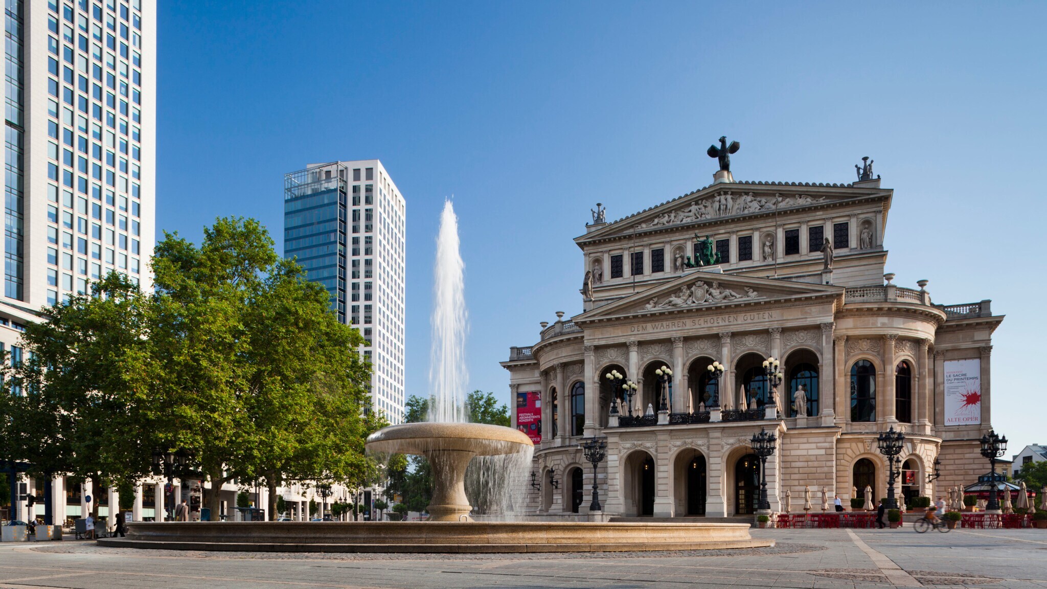 Opernplatz mit Springbrunnen und dahinterliegend das historische Gebäude der Alten Oper Frankfurt.