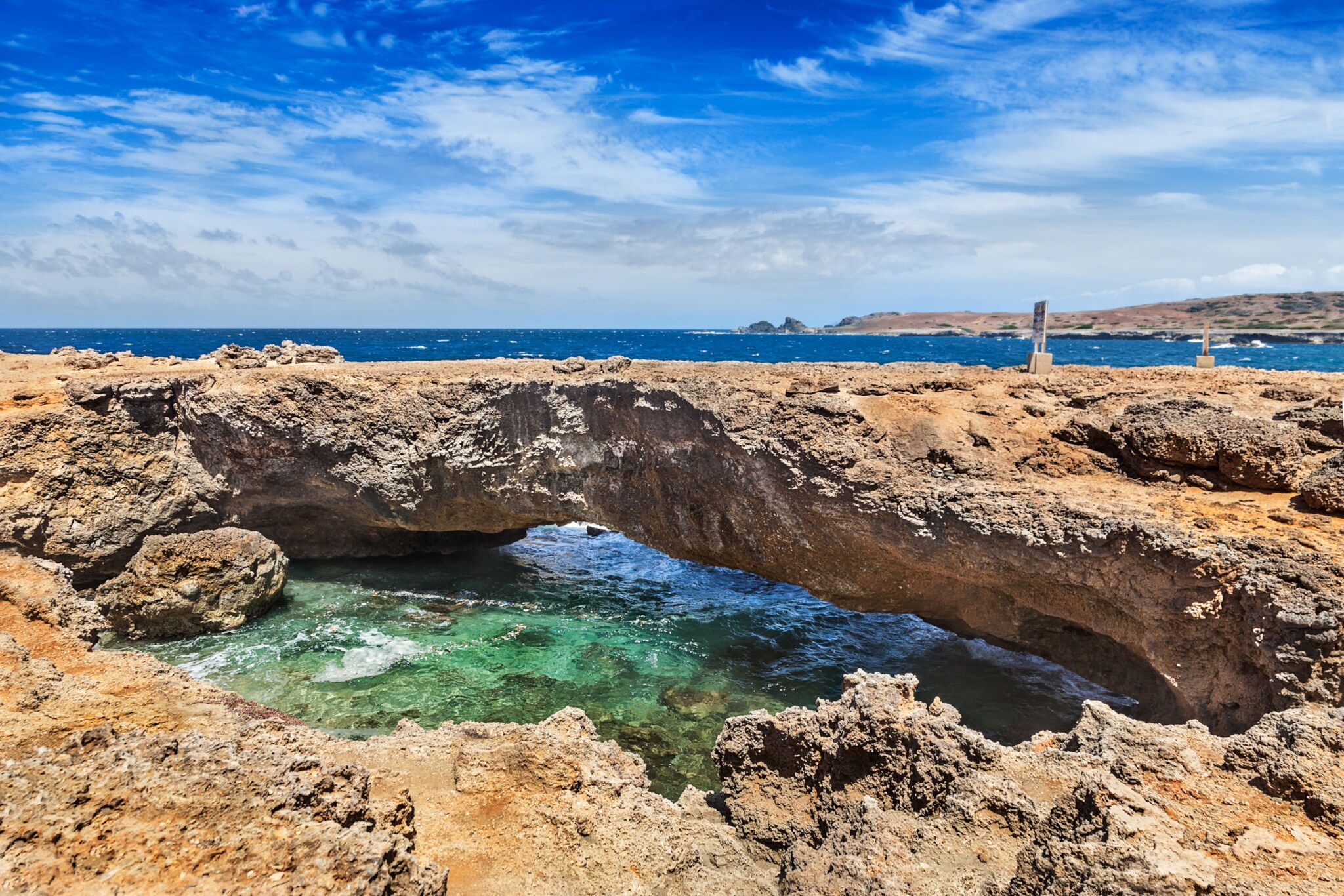 Blick auf eine Felsformation, die wie eine kleine Brücke übers Meer geht.