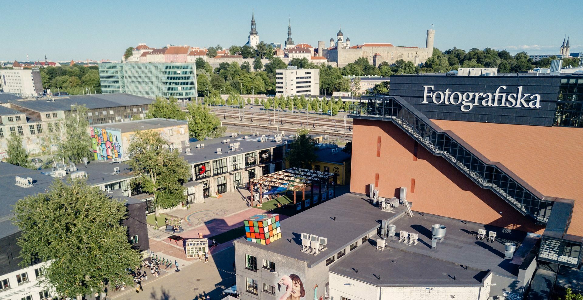 Blick auf den Gebäudekomplex Telliskivi in Tallin bei Dämmerung, im Hintergrund die Stadtmauer und Altstadt.