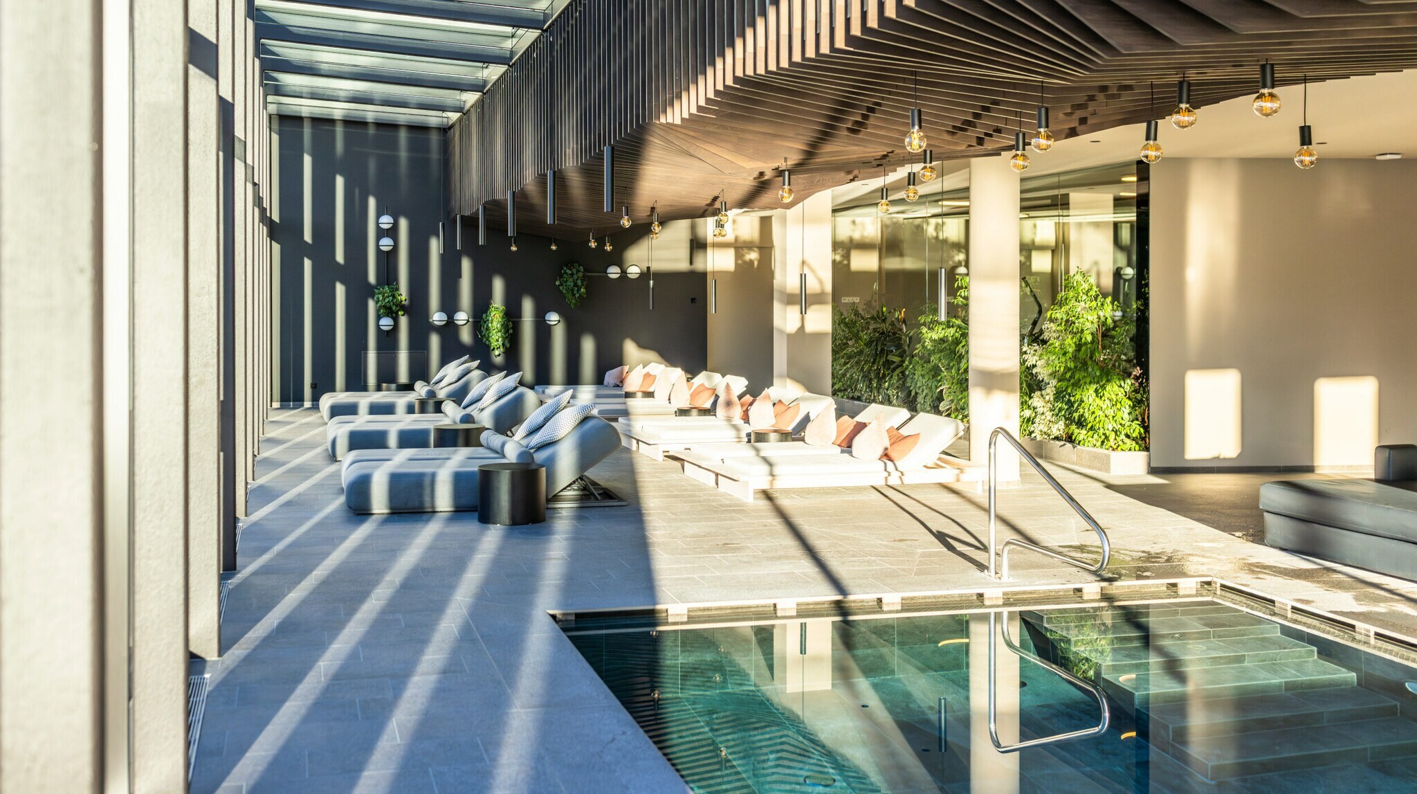 Großzügiger Spa-Bereich mit Pool, Liegen und viel Tageslicht.