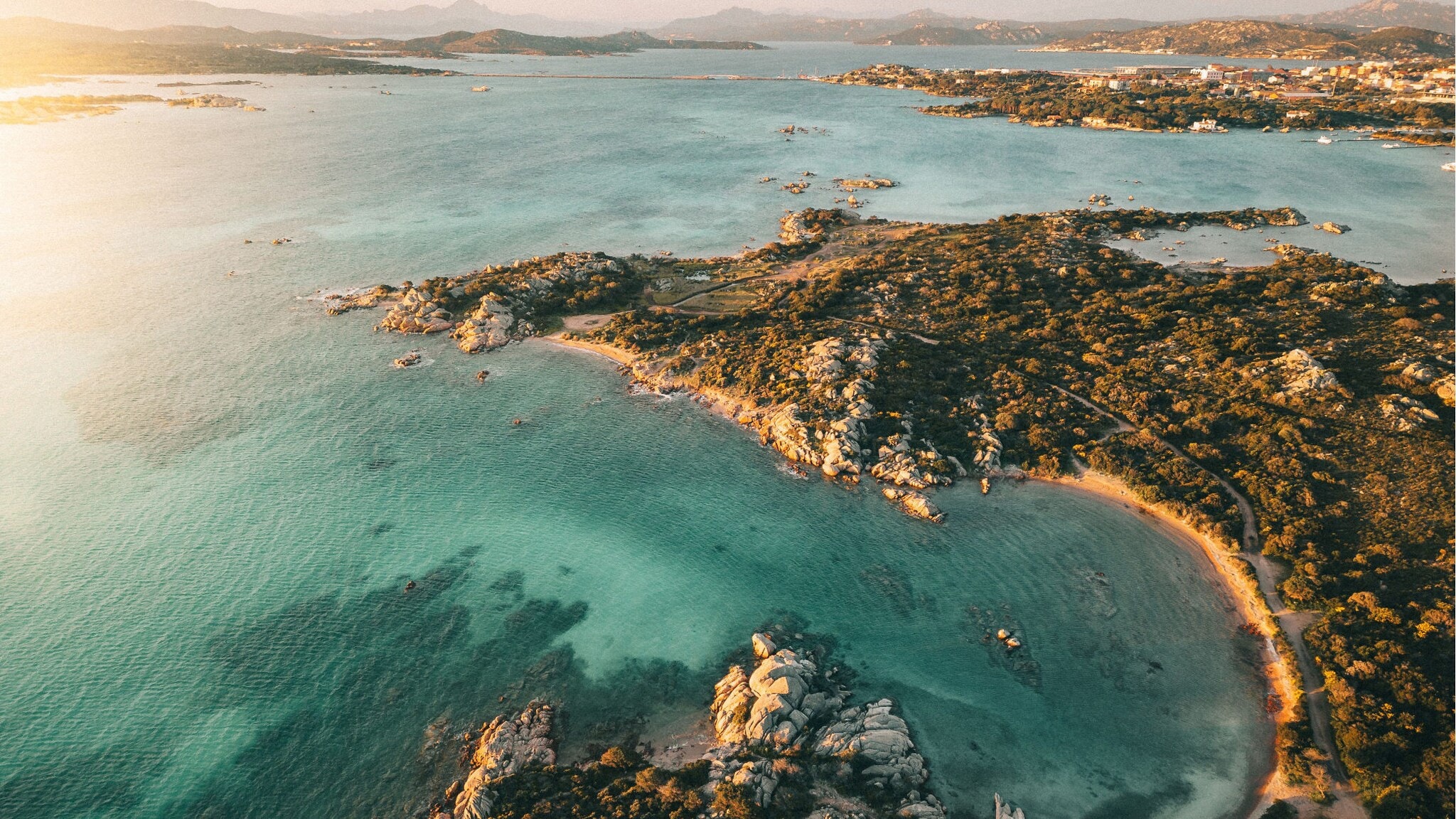 Luftaufnahme einer felsigen Küstenlinie mit klarem, türkisfarbenem Wasser und kleinen Buchten bei Sonnenuntergang. Luftaufnahme einer felsigen Küstenlinie mit klarem, türkisfarbenem Wasser und kleinen Buchten bei Sonnenuntergang.