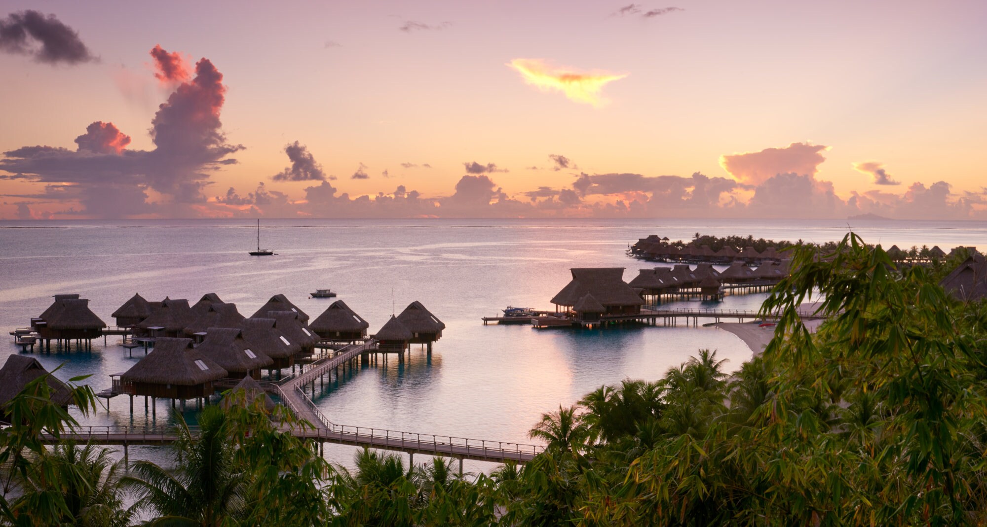 Blick auf die Anlage des Conrad Bora Bora Nui in der Dämmerung, mit seinen friedlich gelegenen Villen auf dem Wasser
