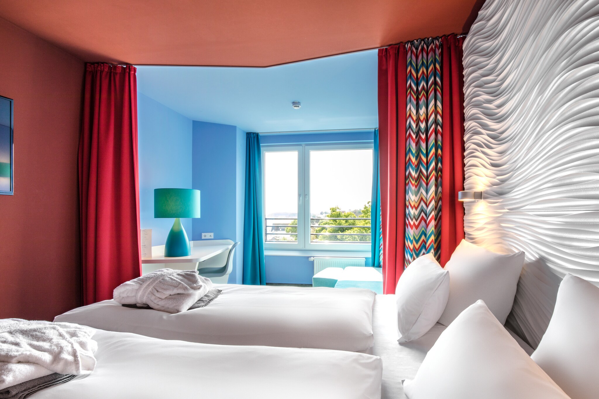 Modernes Hotelzimmer mit farbenfrohen Wänden und Strandblick.