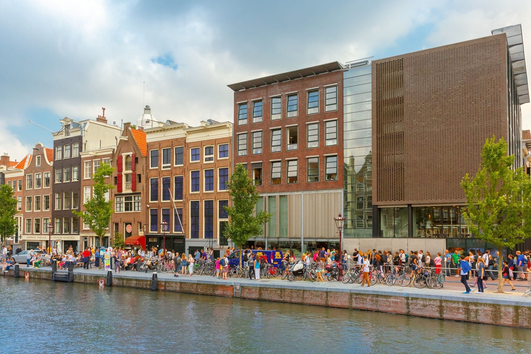 Viele Personen auf einer Promenade an einem Kanal vor dem Museum des Anne-Frank-Hauses.