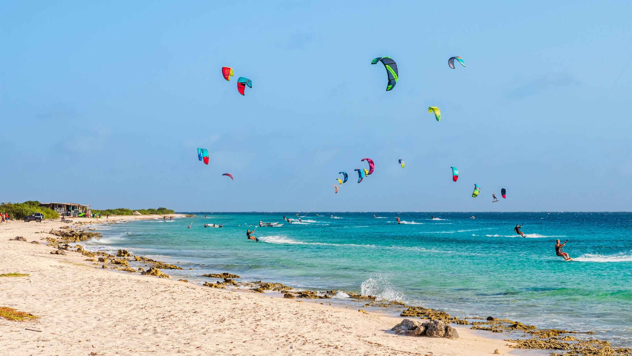 Zahlreiche Kitesurfende im türkisblauen Meer.