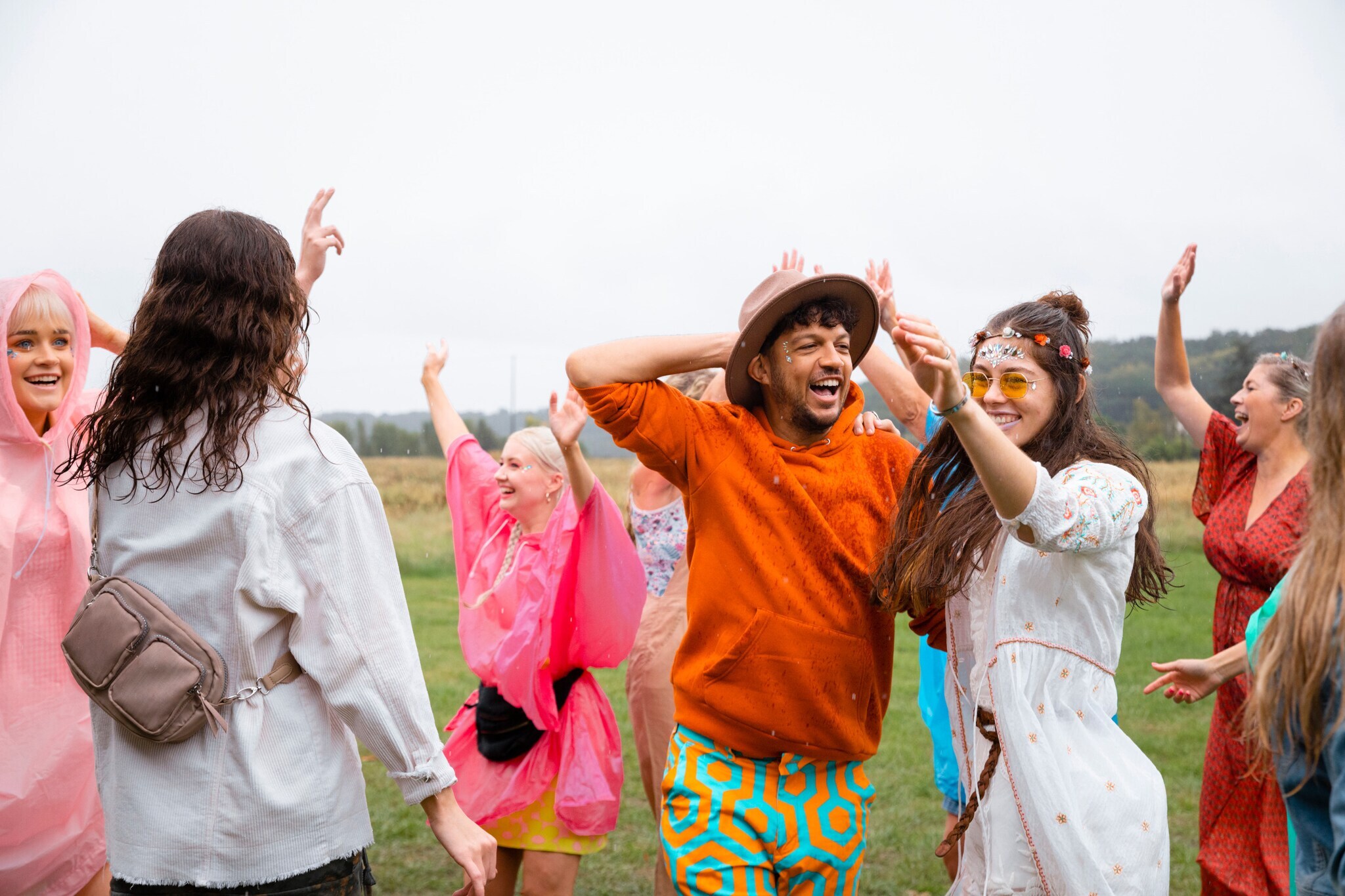 Menschen tanzen im Regen, manche tragen einen Regenponcho.