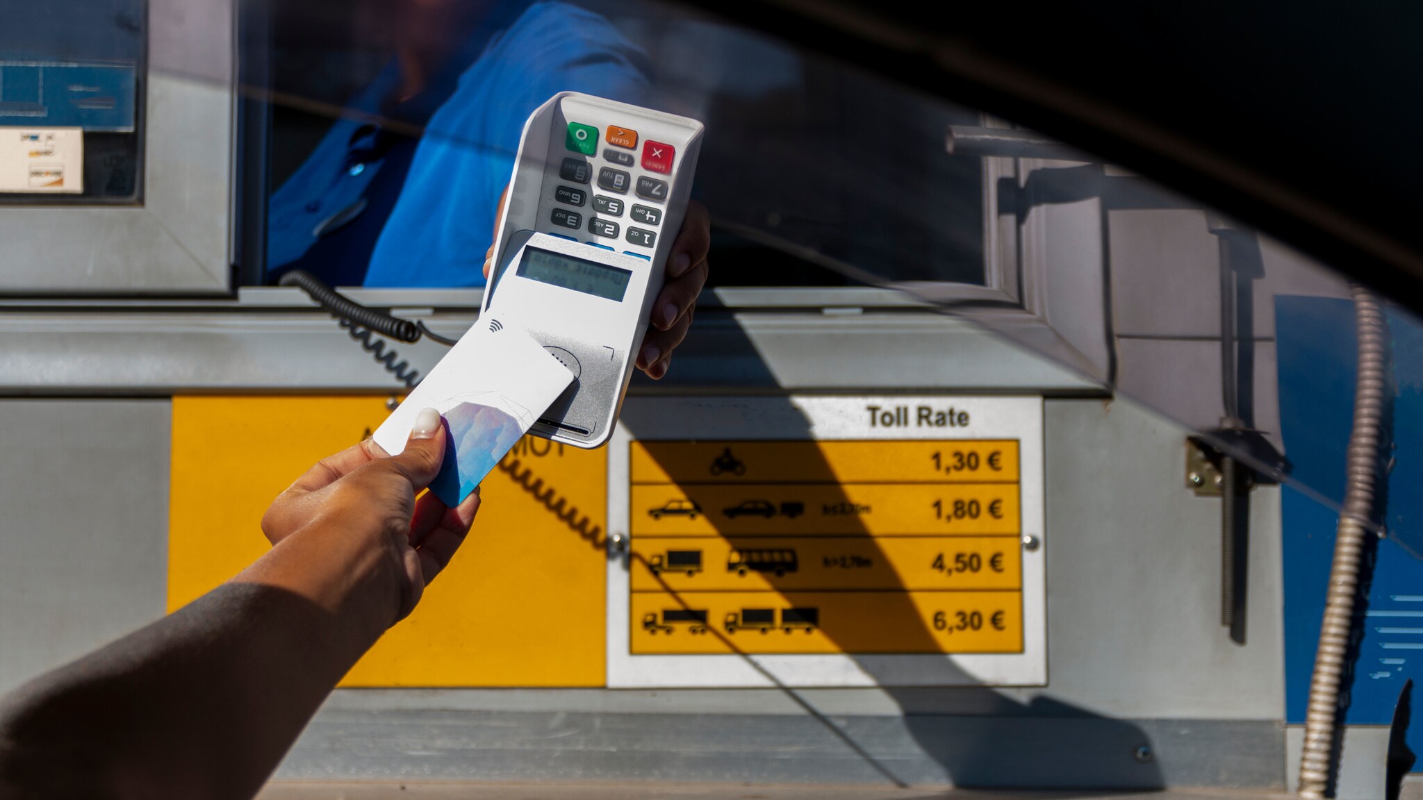 Kontaktlose Zahlung mit Kreditkarte bei einer Person an einer Mautstelle.
