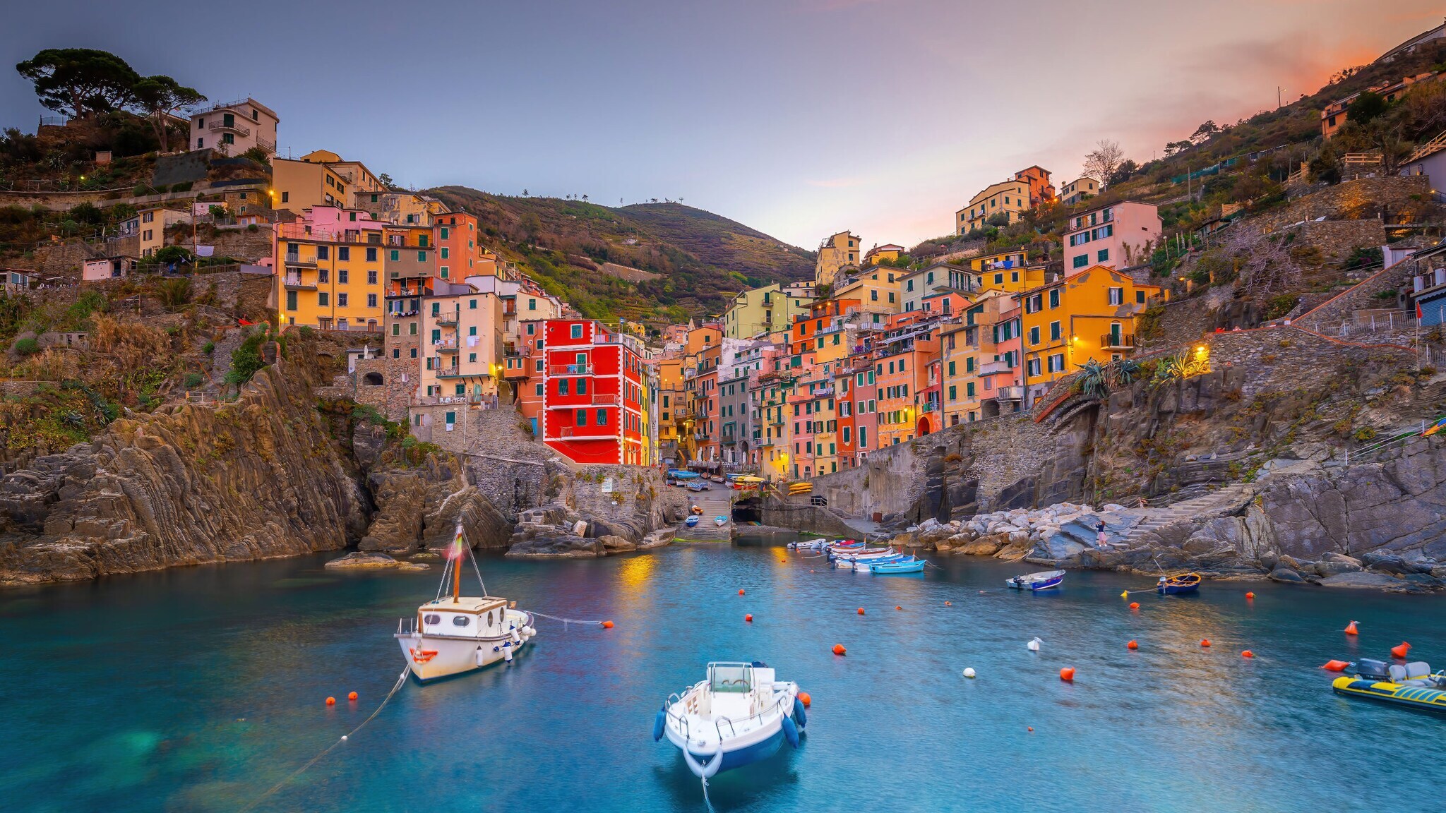 Ortschaft mit bunten Häusern im mediterranen Stil an einer Felsküste mit Meeresbucht mit Fischerbooten im Abendlicht. Ortschaft mit bunten Häusern im mediterranen Stil an einer Felsküste mit Meeresbucht mit Fischerbooten im Abendlicht.