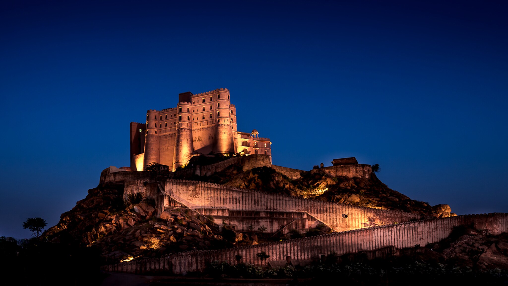 Beleuchtete Festung auf einem Hügel bei Nacht vor klarem, dunklem Himmel