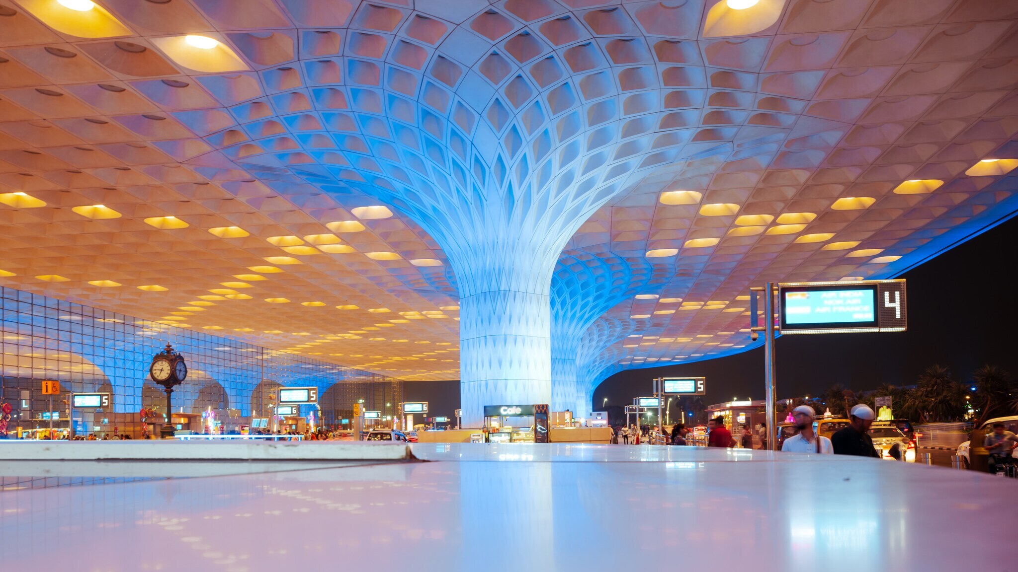 Großes, modernes Flughafen-Terminal in Mumbai mit markanter, baumförmiger Säule und blau-gelber Beleuchtung.