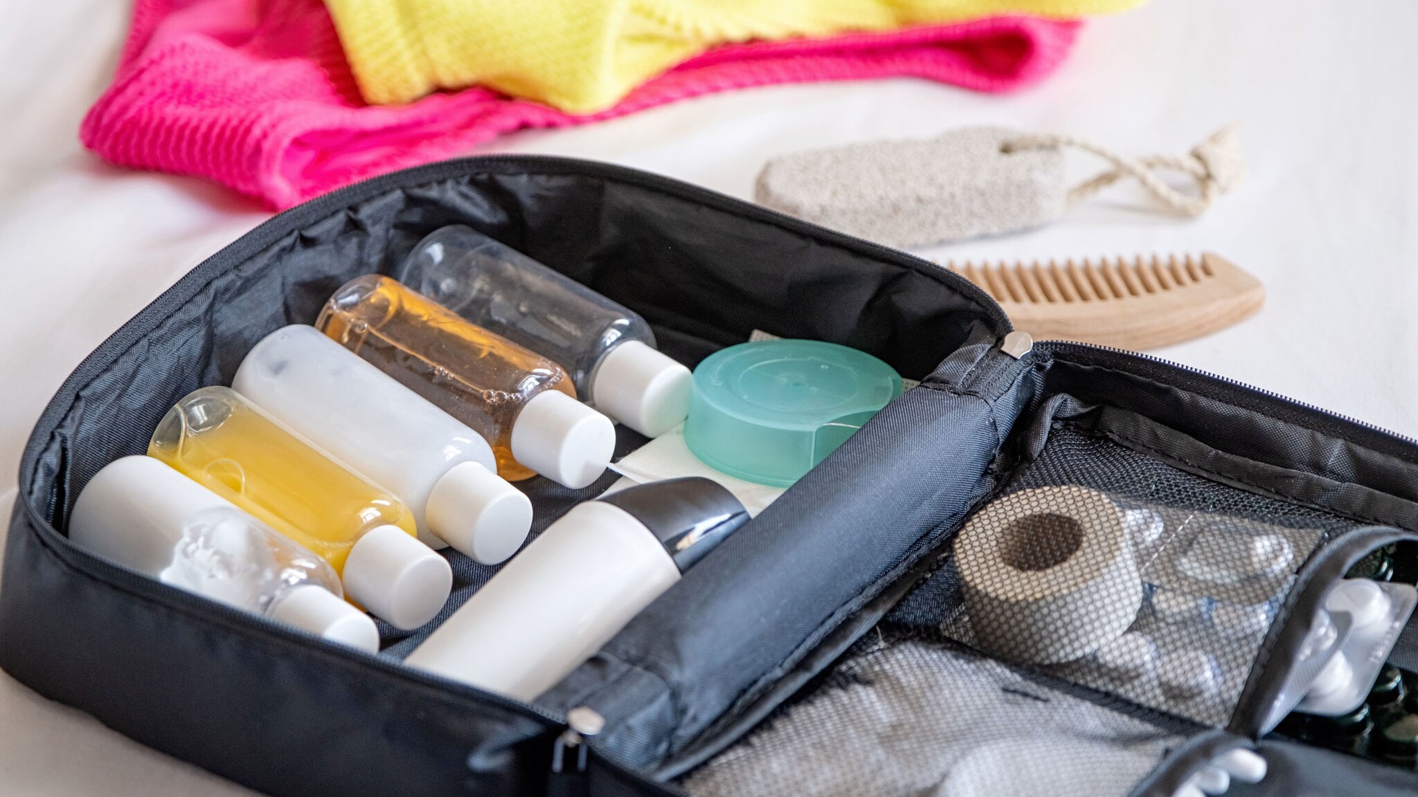 Nahaufnahme einer Kosmetiktasche mit gefüllten Plastikflaschen im Reiseformat.