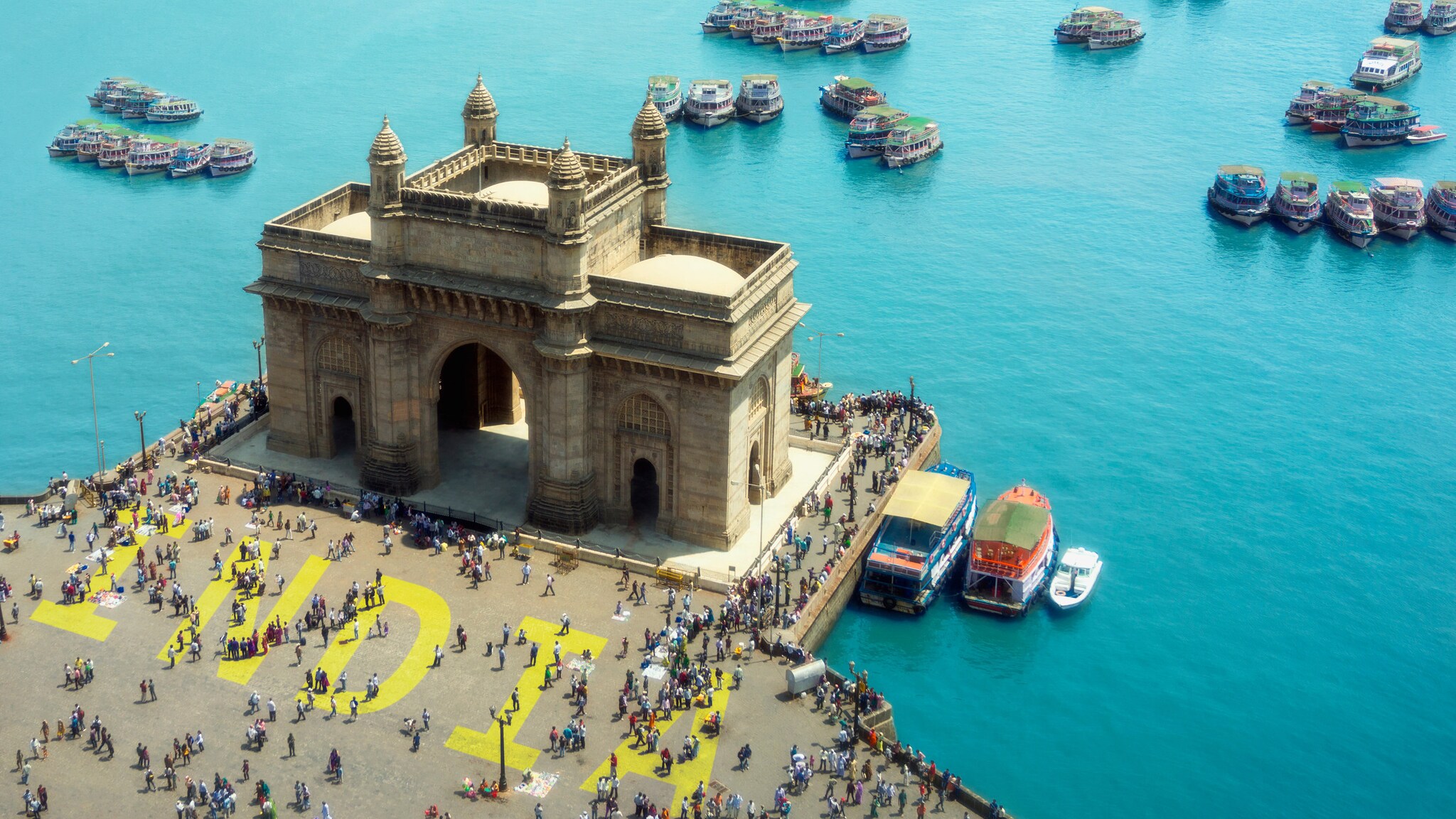 Das Gateway of India, ein großes Tor mit Bögen und Türmen, umgeben von Menschen und Booten im Wasser in Mumbai. Das Gateway of India, ein großes Tor mit Bögen und Türmen, umgeben von Menschen und Booten im Wasser in Mumbai.