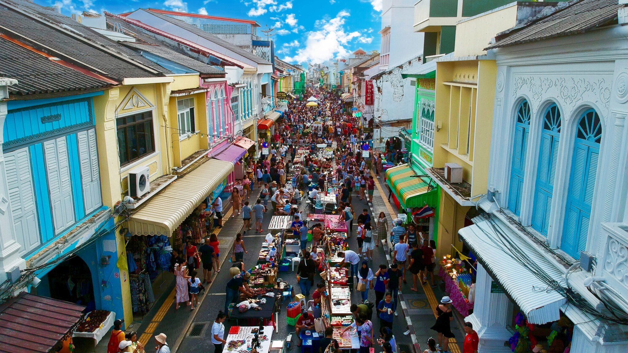 Schmale Straße im Stadtzentrum mit Markttreiben zwischen bunten Hausfassaden.