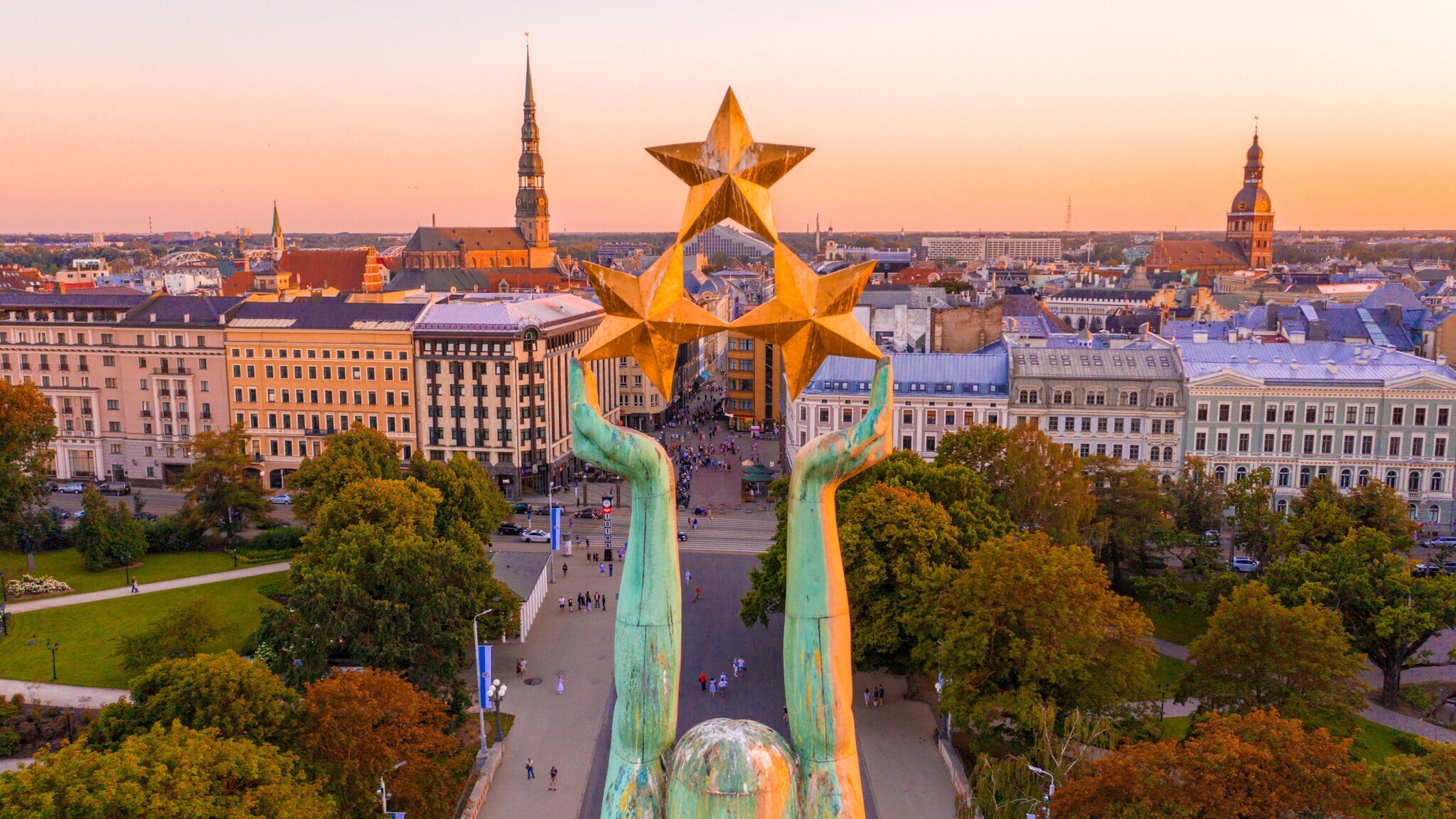 Stadtpanorama von Riga mit Altstadt aus der Luft, im Vordergrund die Arme einer Freiheitsstatue mit drei Sternen. Stadtpanorama von Riga mit Altstadt aus der Luft, im Vordergrund die Arme einer Freiheitsstatue mit drei Sternen.