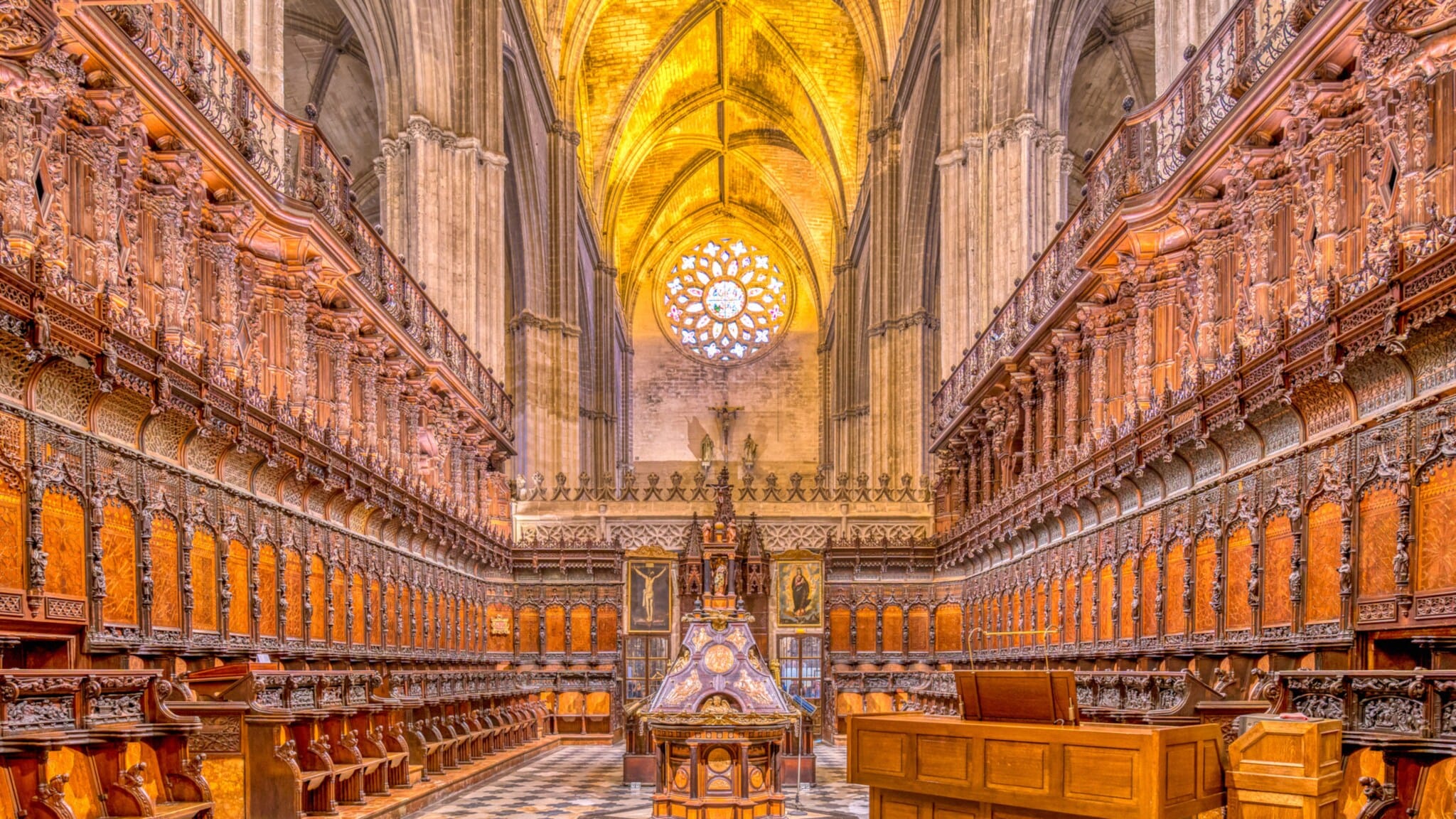 Innenraum einer gotischen Kathedrale mit reich verzierten Holzsitzreihen und gewölbten Deckenbogen mit goldener Beleuchtung Innenraum einer gotischen Kathedrale mit reich verzierten Holzsitzreihen und gewölbten Deckenbogen mit goldener Beleuchtung