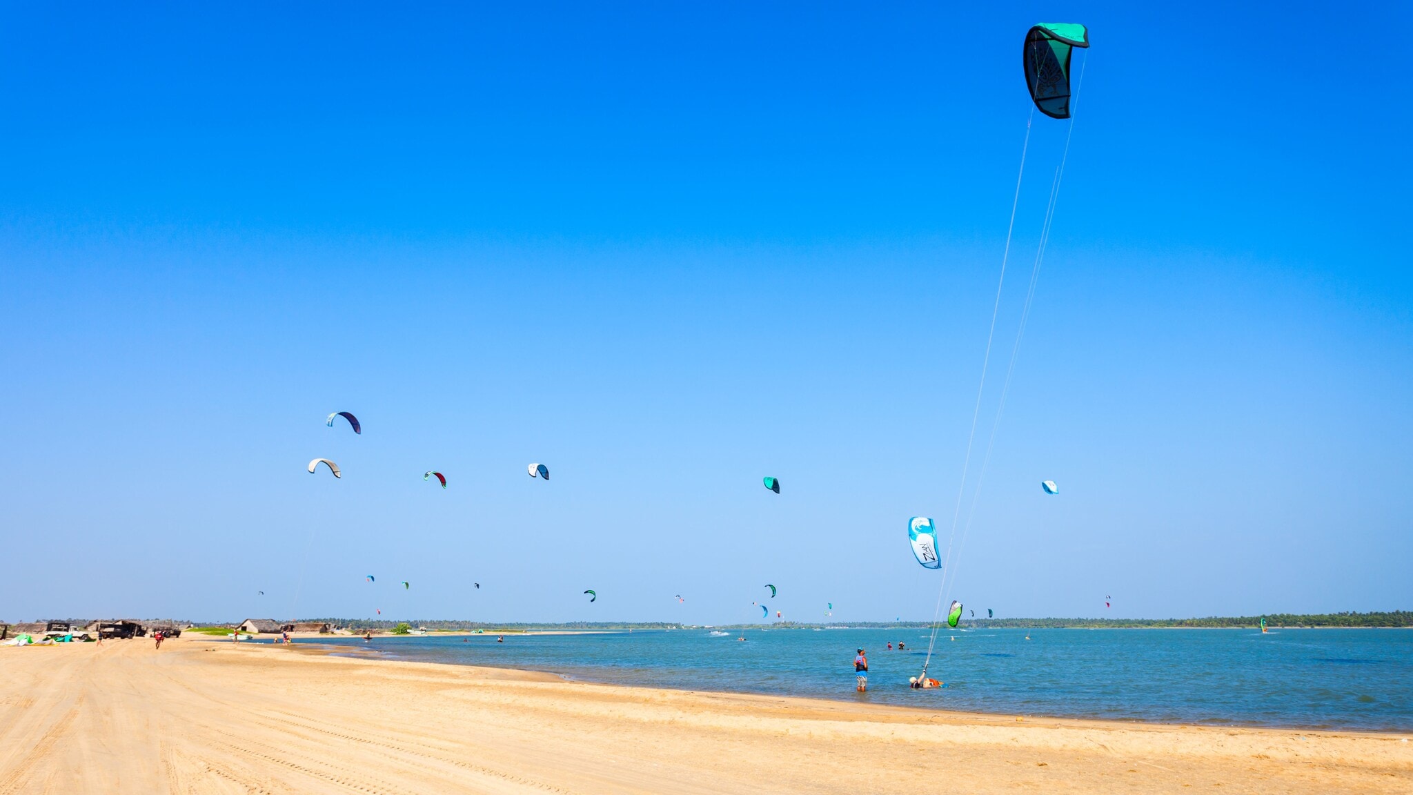 Zahlreiche Kitesurfende an einem breiten Sandstrand. Zahlreiche Kitesurfende an einem breiten Sandstrand.