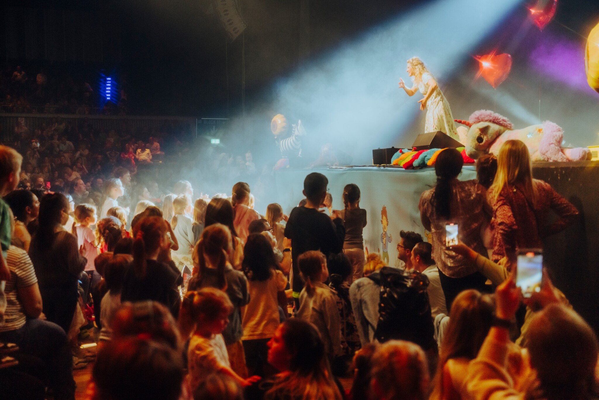 Simone Sommerland steht am Rand der Bühne, viele Kinder schauen ihr aus dem Publikum gebannt zu.