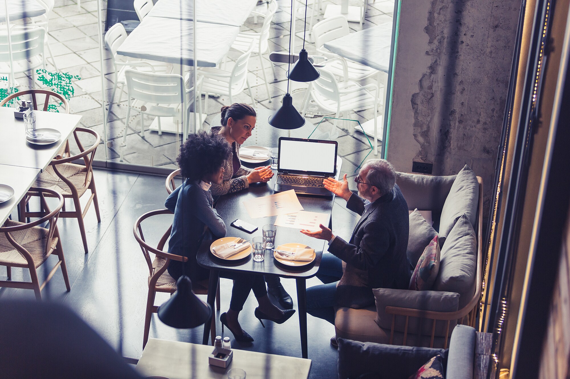Zukunft für Familienunternehmen: So klappt die Nachfolge Mehrere Personen sitzen in einem Café für ein Arbeitsmeeting.