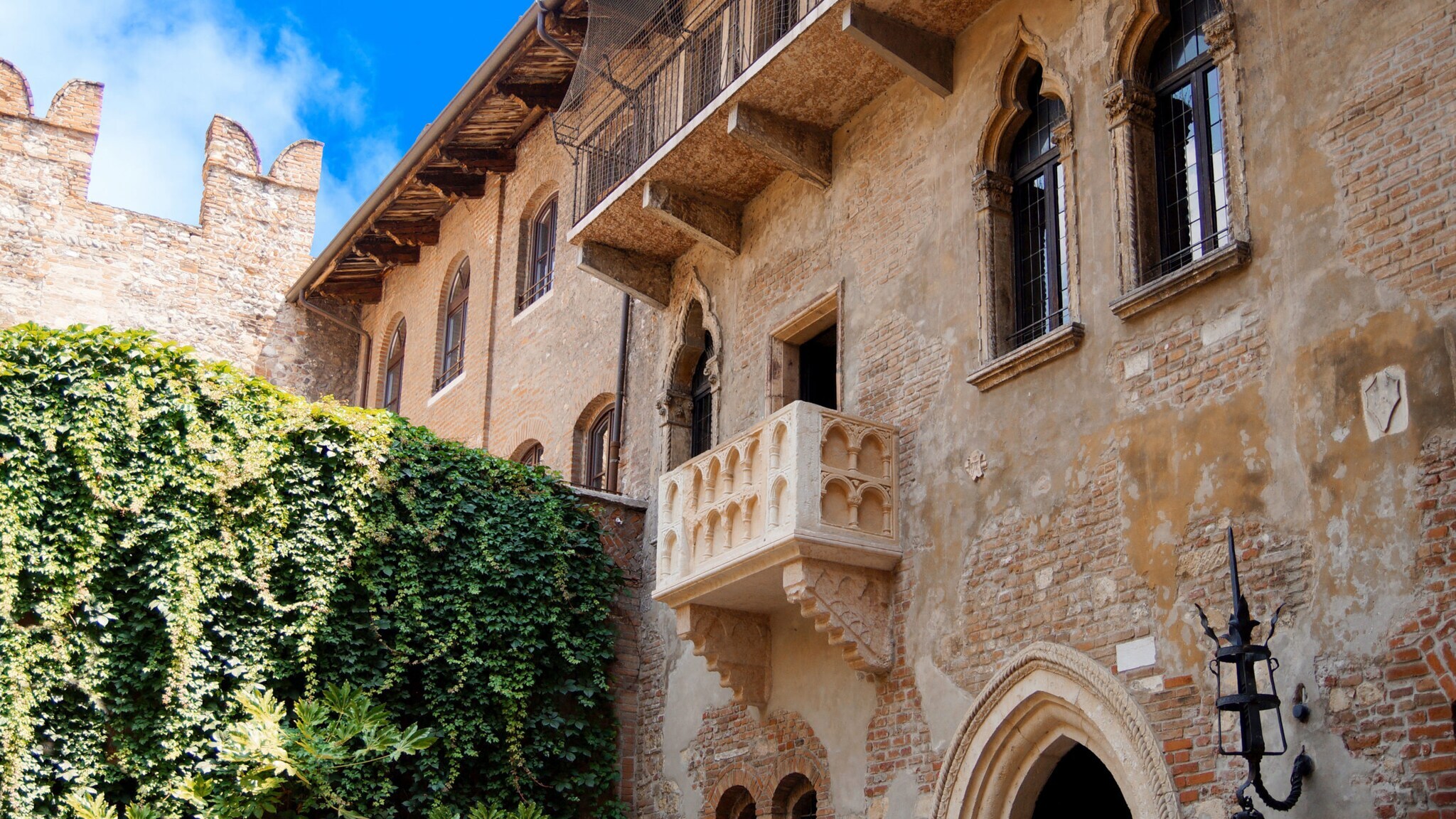 Steinbalkon an einer historischen Hausfassade in einem begrünten Innenhof.
