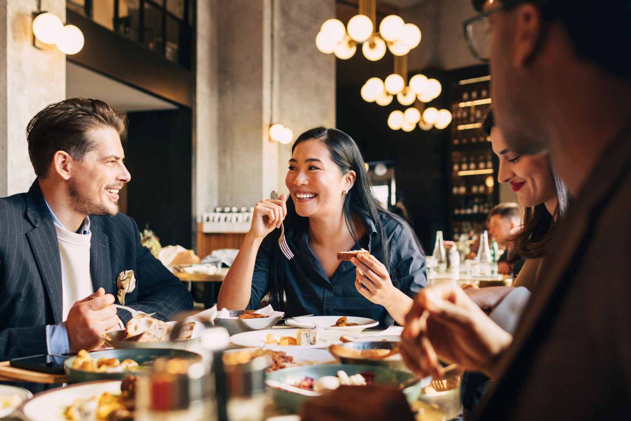 Vier fröhliche Menschen an einem Tisch im Restaurant.