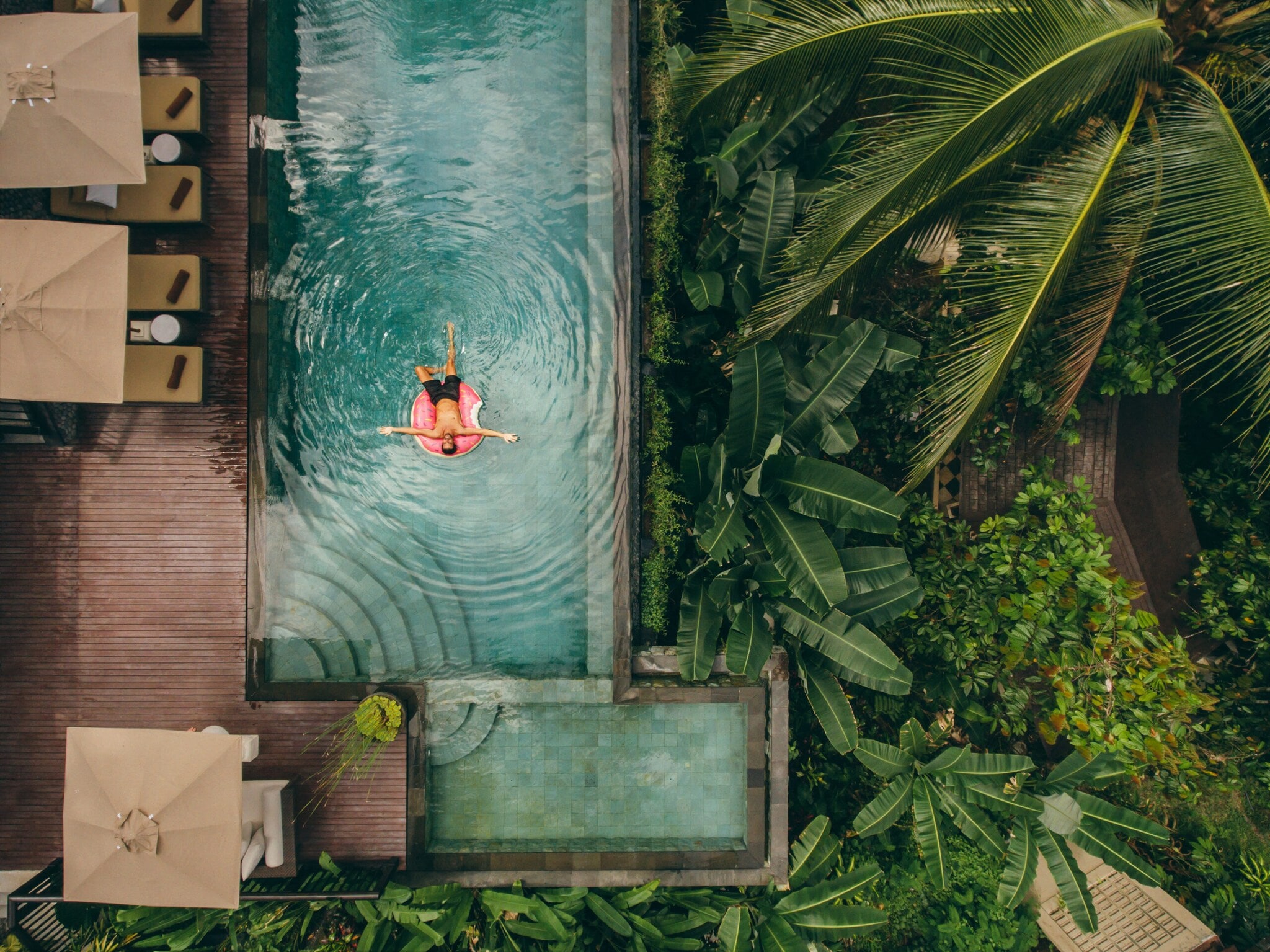 Junger Mann auf einer Luftmatratze in einem Infinity-Pool mit tropischer Umgebung. Junger Mann auf einer Luftmatratze in einem Infinity-Pool mit tropischer Umgebung.
