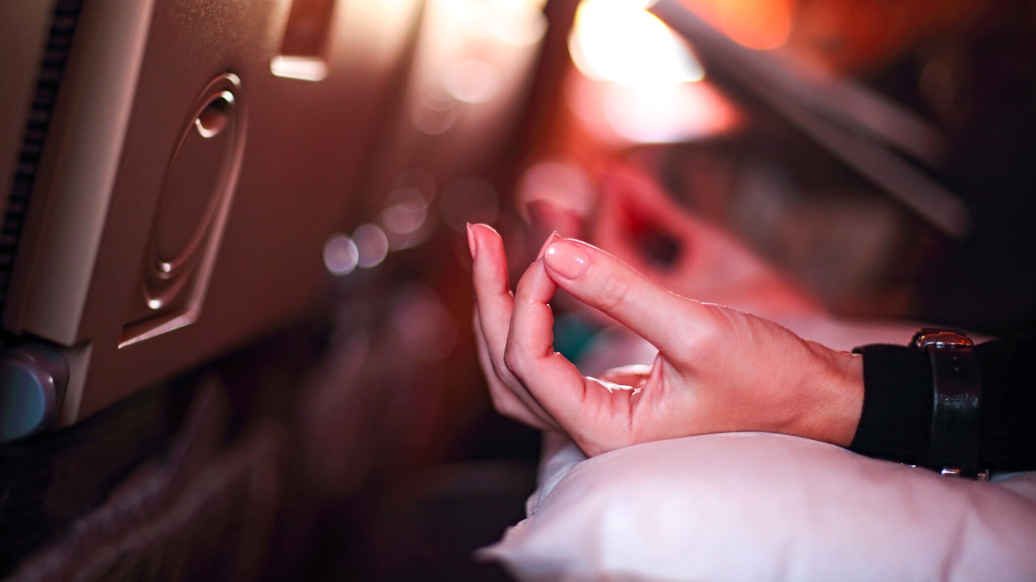 Hand in Meditationshaltung auf einem Kissen in einem Flugzeugsitz Hand in Meditationshaltung auf einem Kissen in einem Flugzeugsitz