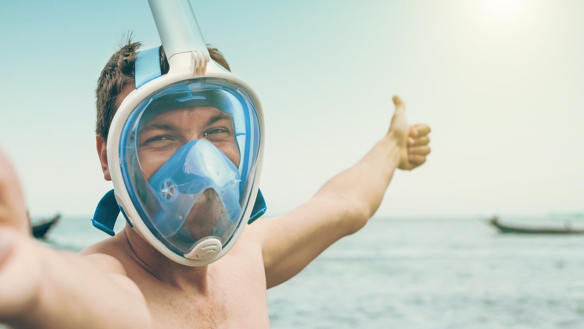 Mann mit Vollgesichts-Schnorchelmaske am Meer, der Daumen hoch zeigt Mann mit Vollgesichts-Schnorchelmaske am Meer, der Daumen hoch zeigt