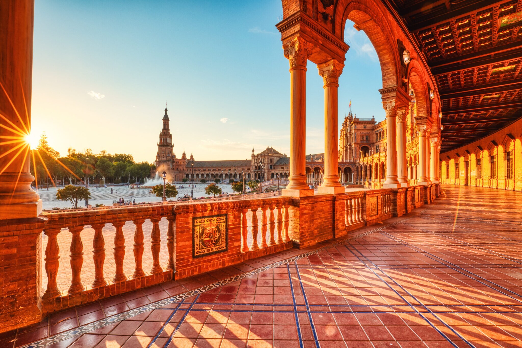 Überdachte Promenade an einem halbkreisförmigen Palastkomplex im andalusischen Stil an einem großen Platz im warmen Licht bei Sonnenuntergang. Überdachte Promenade an einem halbkreisförmigen Palastkomplex im andalusischen Stil an einem großen Platz im warmen Licht bei Sonnenuntergang.