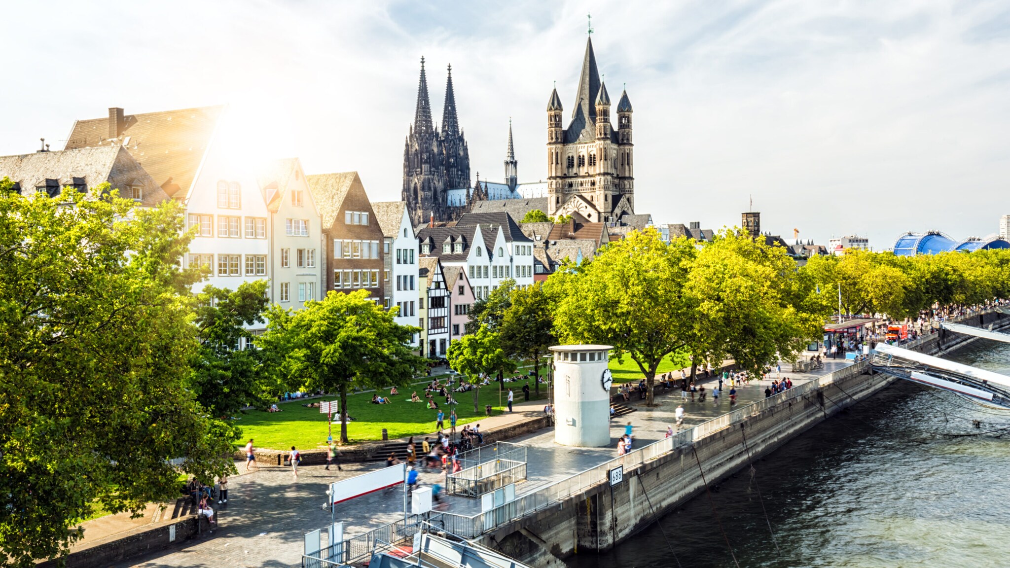 Sonnenlicht über dem Rhein mit Blick auf historische Häuser und den Kölner Dom im Hintergrund Sonnenlicht über dem Rhein mit Blick auf historische Häuser und den Kölner Dom im Hintergrund