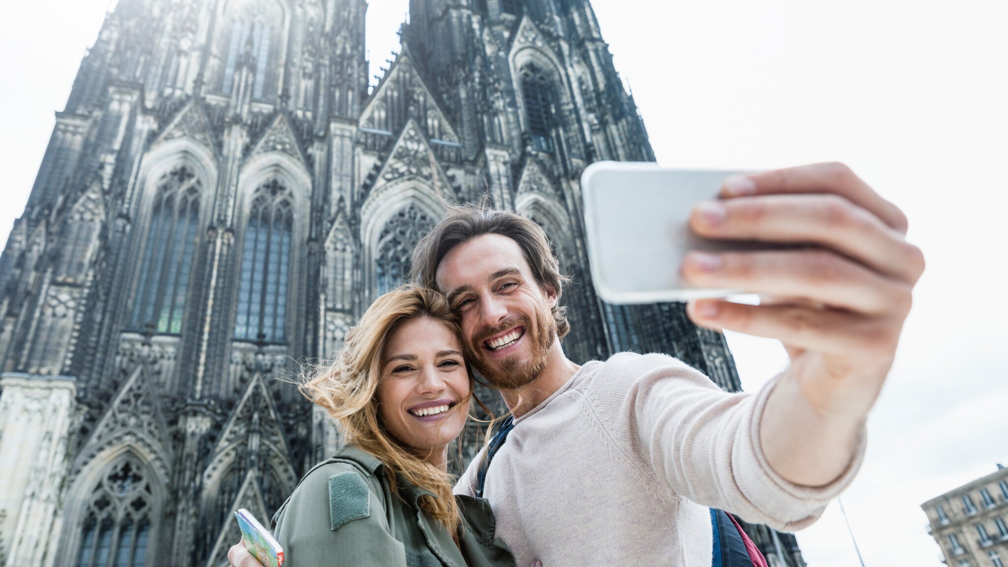 Junges Paar macht Selfie vor dem gotischen Kölner Dom an einem hellen Tag