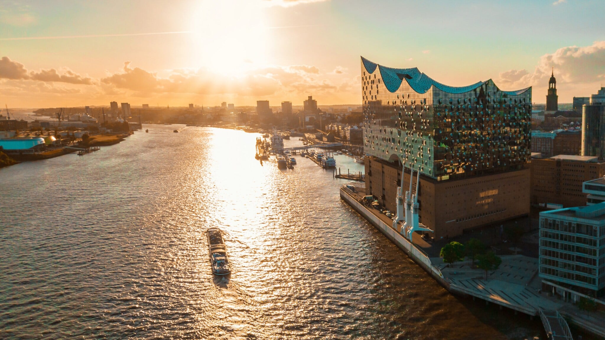 Sonnenuntergang über der Elbphilharmonie in Hamburg mit einem Schiff auf der Elbe und Stadtansicht im Hintergrund. Sonnenuntergang über der Elbphilharmonie in Hamburg mit einem Schiff auf der Elbe und Stadtansicht im Hintergrund.