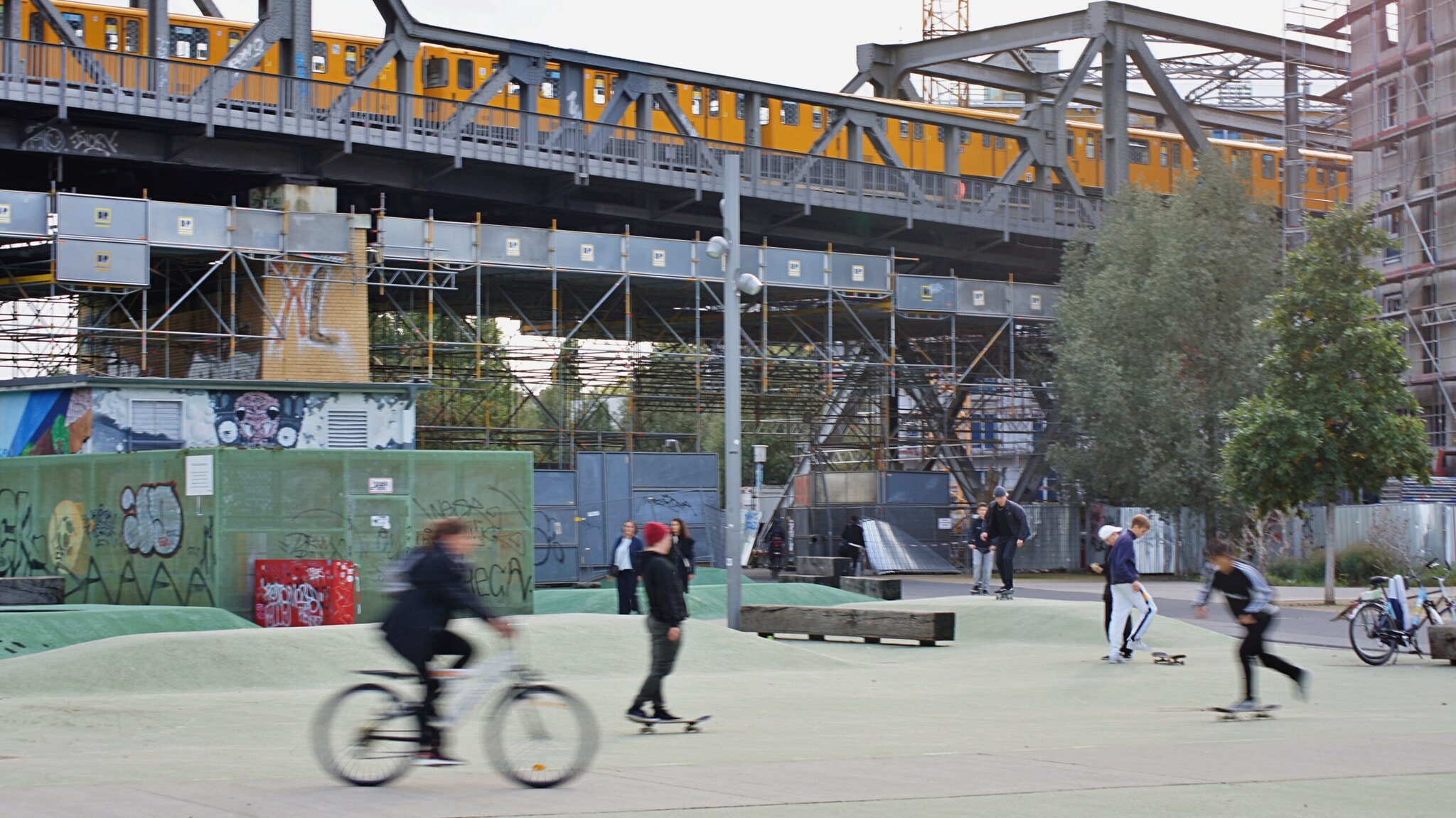Jugendliche fahren Fahrrad und Skateboard auf einem Skaterplatz im Park am Gleisdreieck. Jugendliche fahren Fahrrad und Skateboard auf einem Skaterplatz im Park am Gleisdreieck.