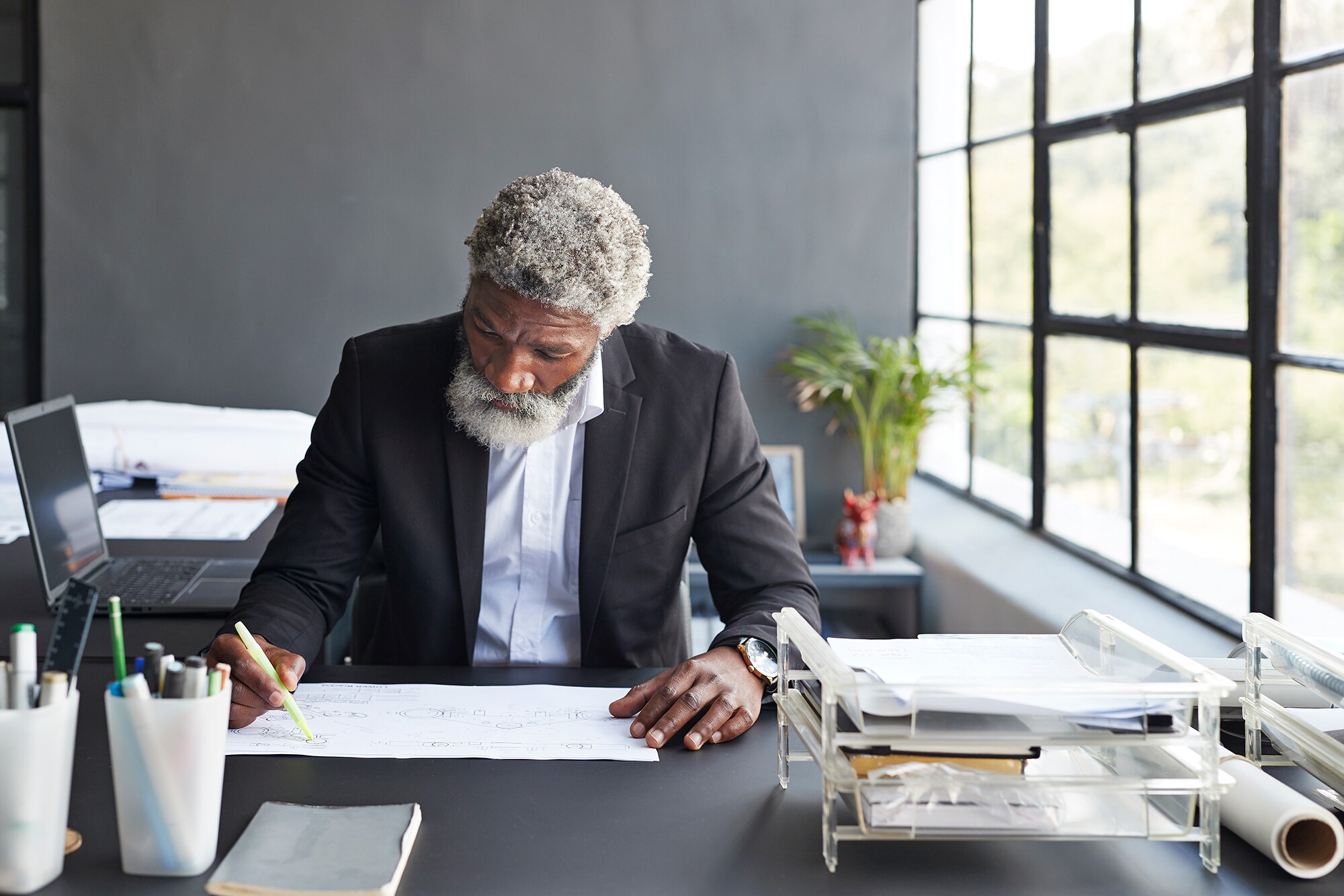 Deep Work im Büroalltag: So kannst du konzentriert arbeiten Ein älterer Mann arbeitet fokussiert im Büro an einer technischen Zeichnung.