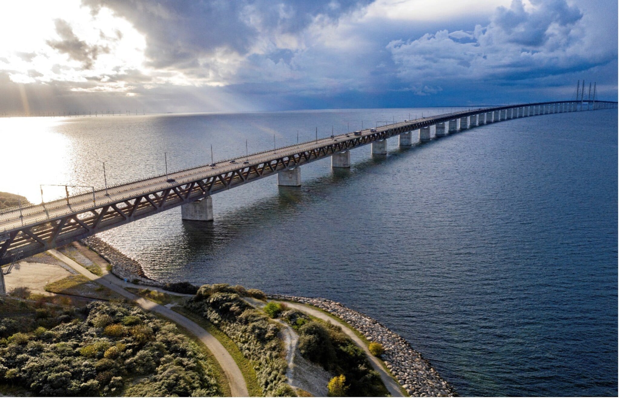 Lange Brücke über ruhiges Meer mit bewölktem Himmel und Sonnenlicht, das durch die Wolken scheint. Lange Brücke über ruhiges Meer mit bewölktem Himmel und Sonnenlicht, das durch die Wolken scheint.