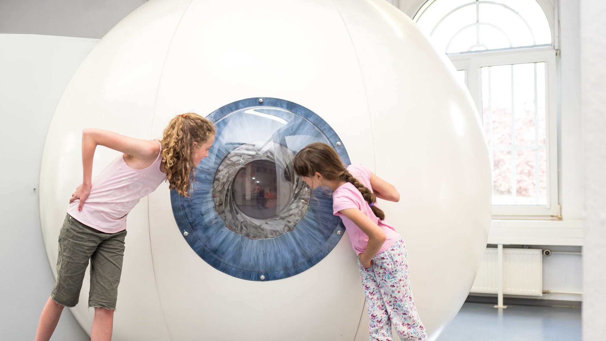 Zwei Mädchen blicken neugierig in ein großes, begehbares Modell eines menschlichen Auges im Museum EXPERIMINTA