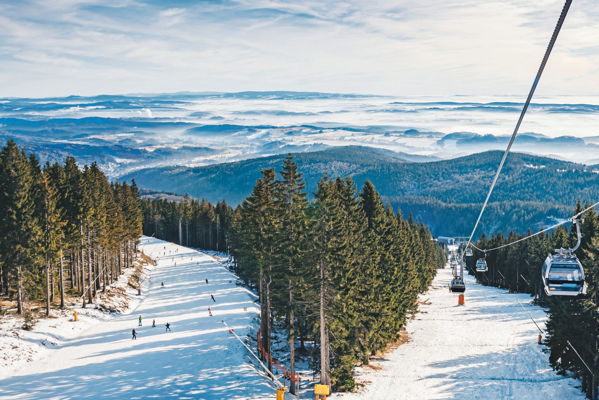 Eine Piste mit Skifahrern und Skilift zwischen Wäldern. Eine Piste mit Skifahrern und Skilift zwischen Wäldern.