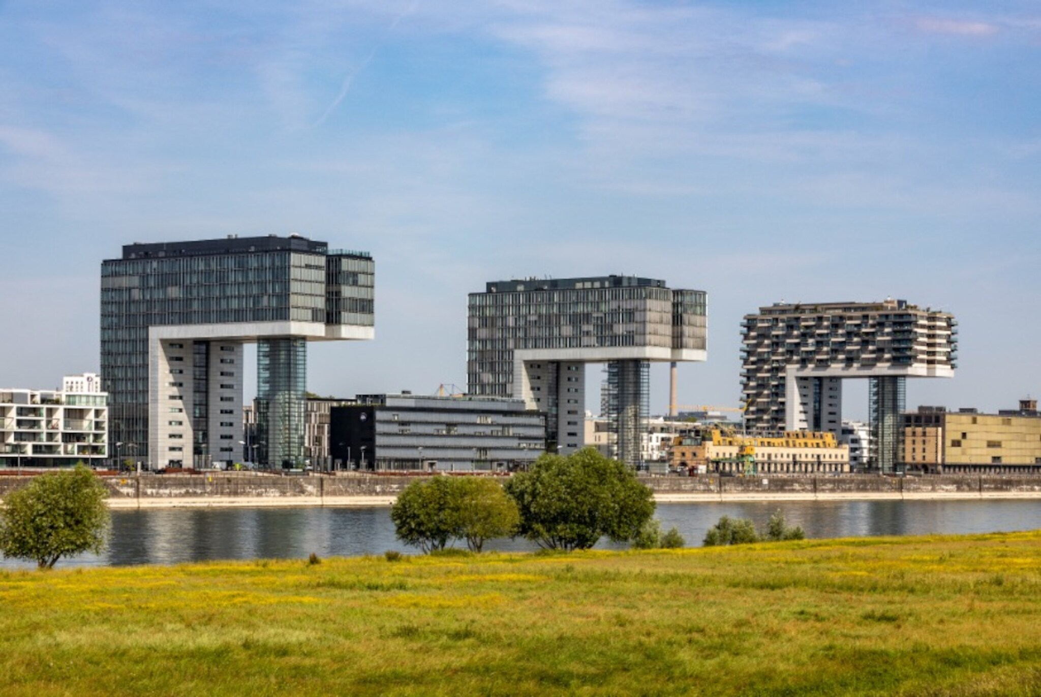 Drei moderne Bürogebäude am Rheinufer in Köln, darunter die Kranhäuser mit markanter Architektur