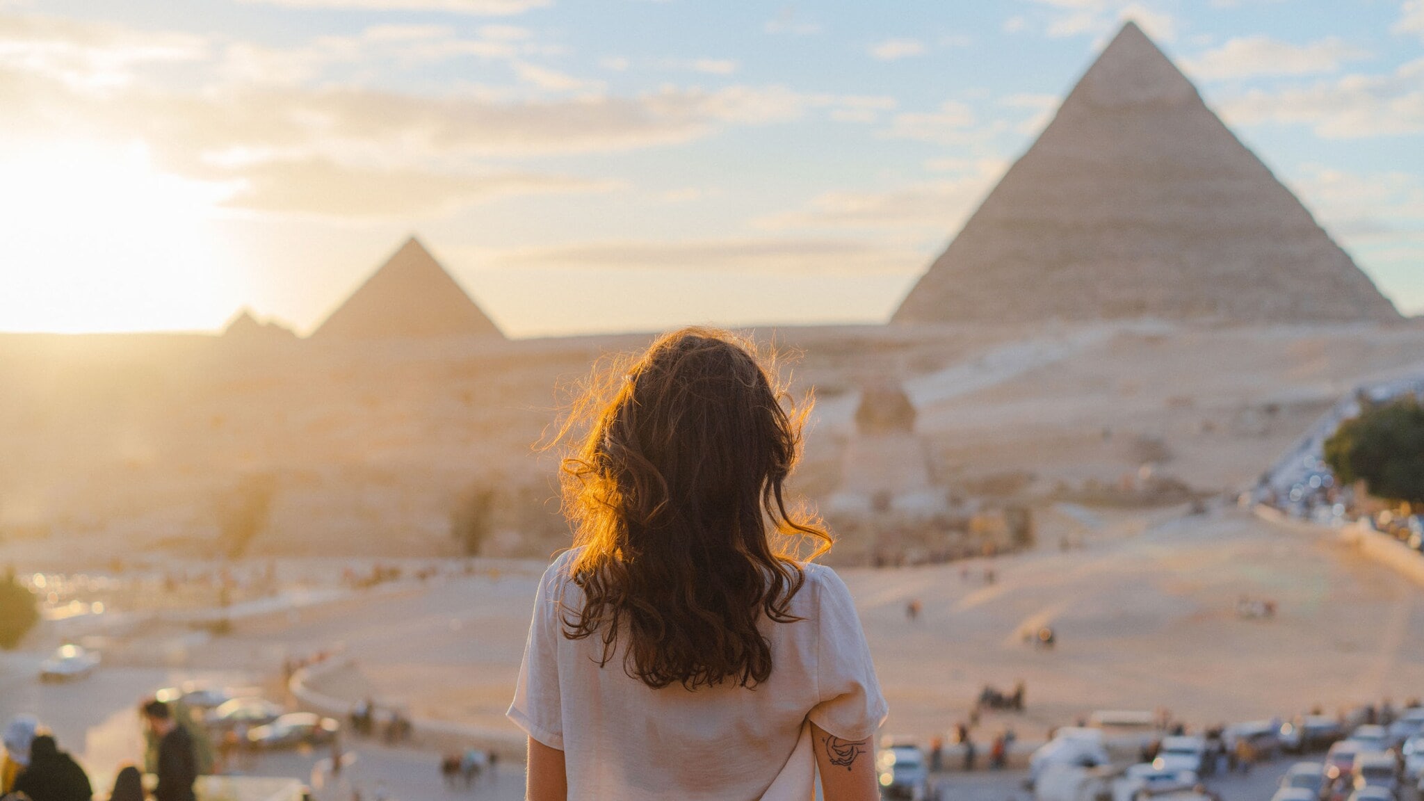 Frau mit lockigem Haar blickt auf die Pyramiden von Gizeh bei Sonnenuntergang Frau mit lockigem Haar blickt auf die Pyramiden von Gizeh bei Sonnenuntergang