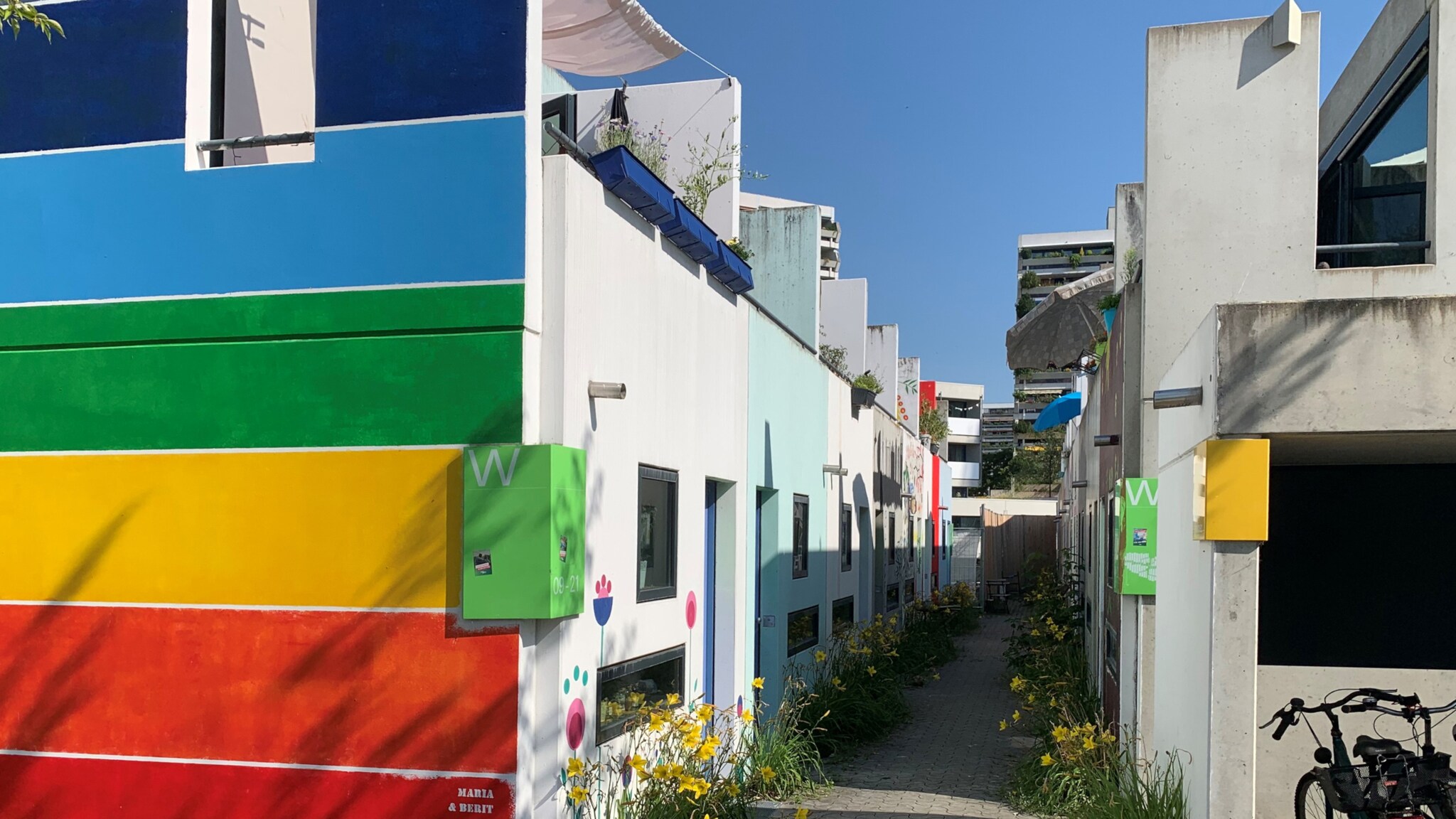Bunte Fassaden von Studentenwohnungen im Olympischen Dorf München mit Blumen und Fahrrad im Vordergrund